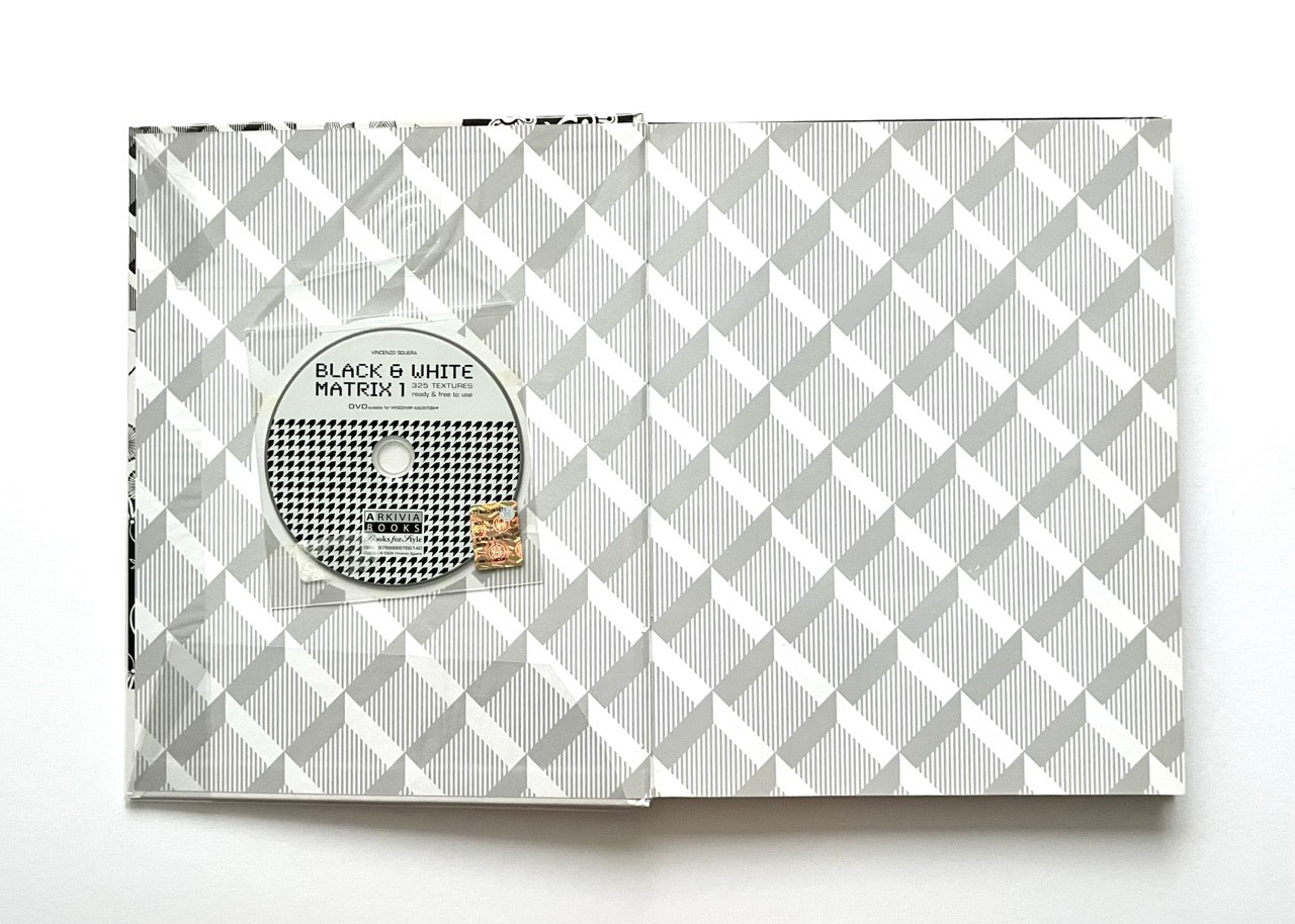 Open 'Black & White Matrix 1' book showing patterned endpapers with a CD attached to it.