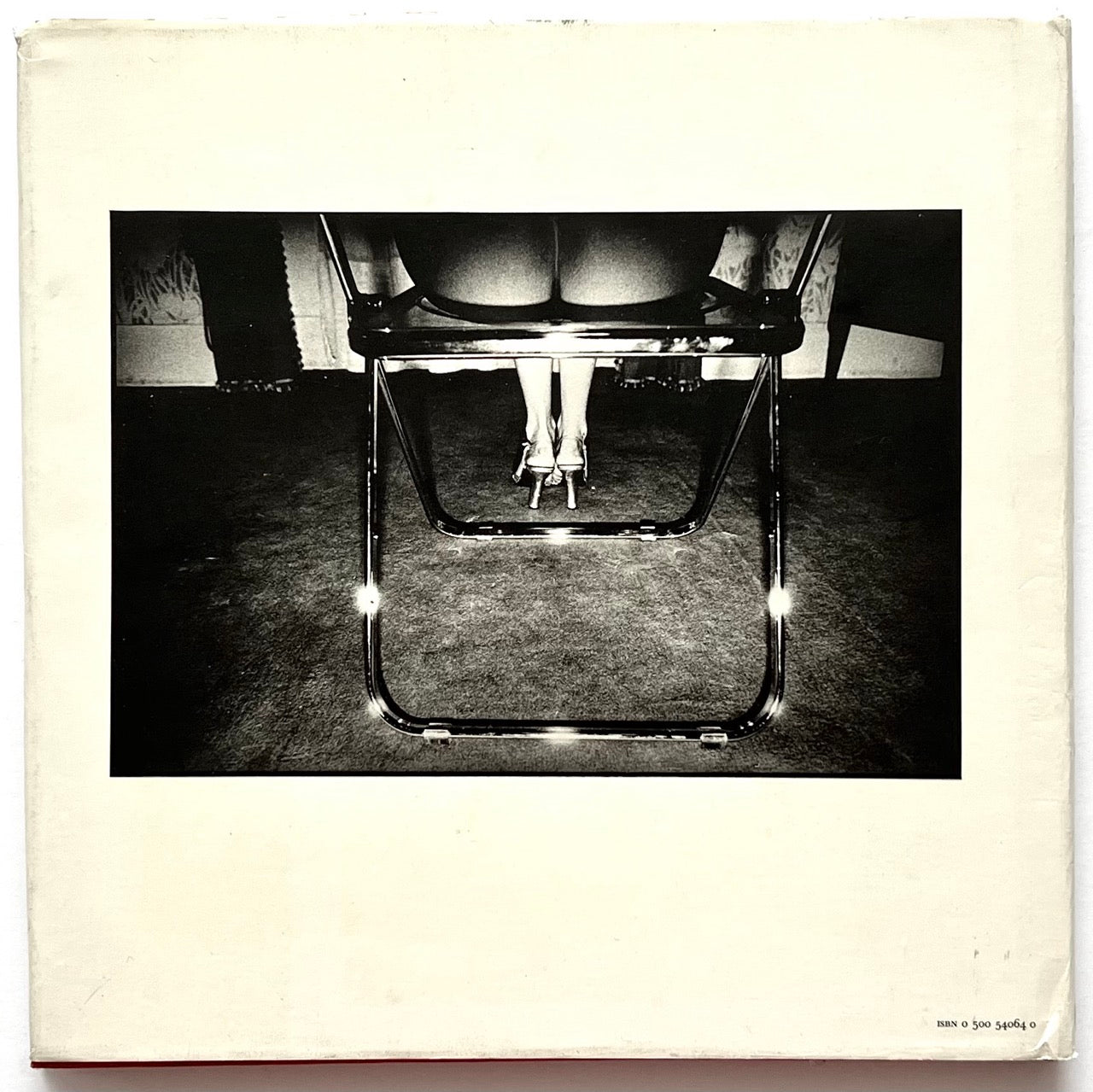 David Bailey’s Trouble and Strife, first edition published in 1980. Back cover of iconic photography monograph showing black-and-white image of a seated woman’s legs and heels beneath a chrome chair in dramatic high-contrast lighting.