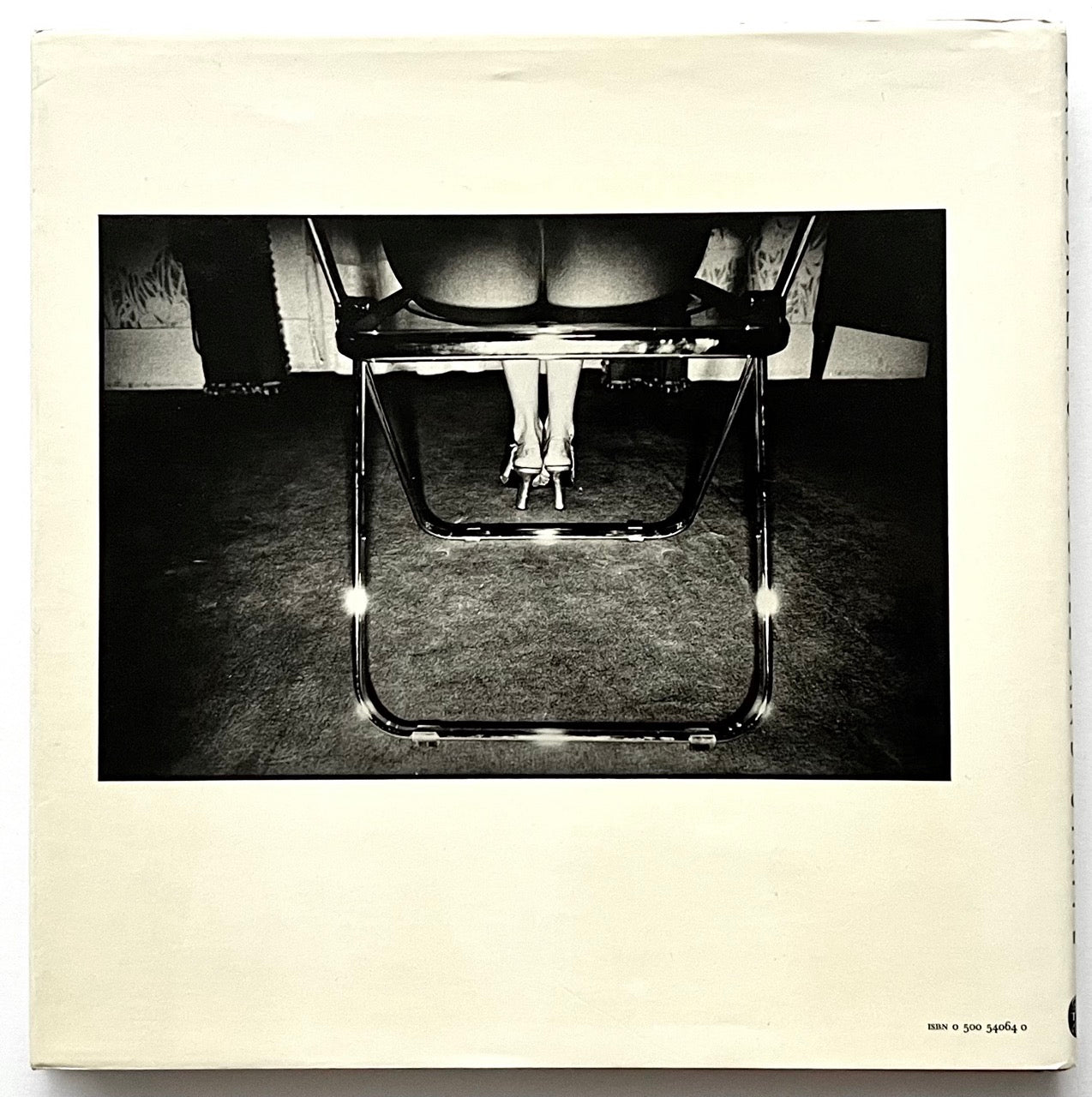 Rear cover of David Bailey's Trouble and Strife' with b black and white photo of a metal chair with legs in high heels on a textured floor.