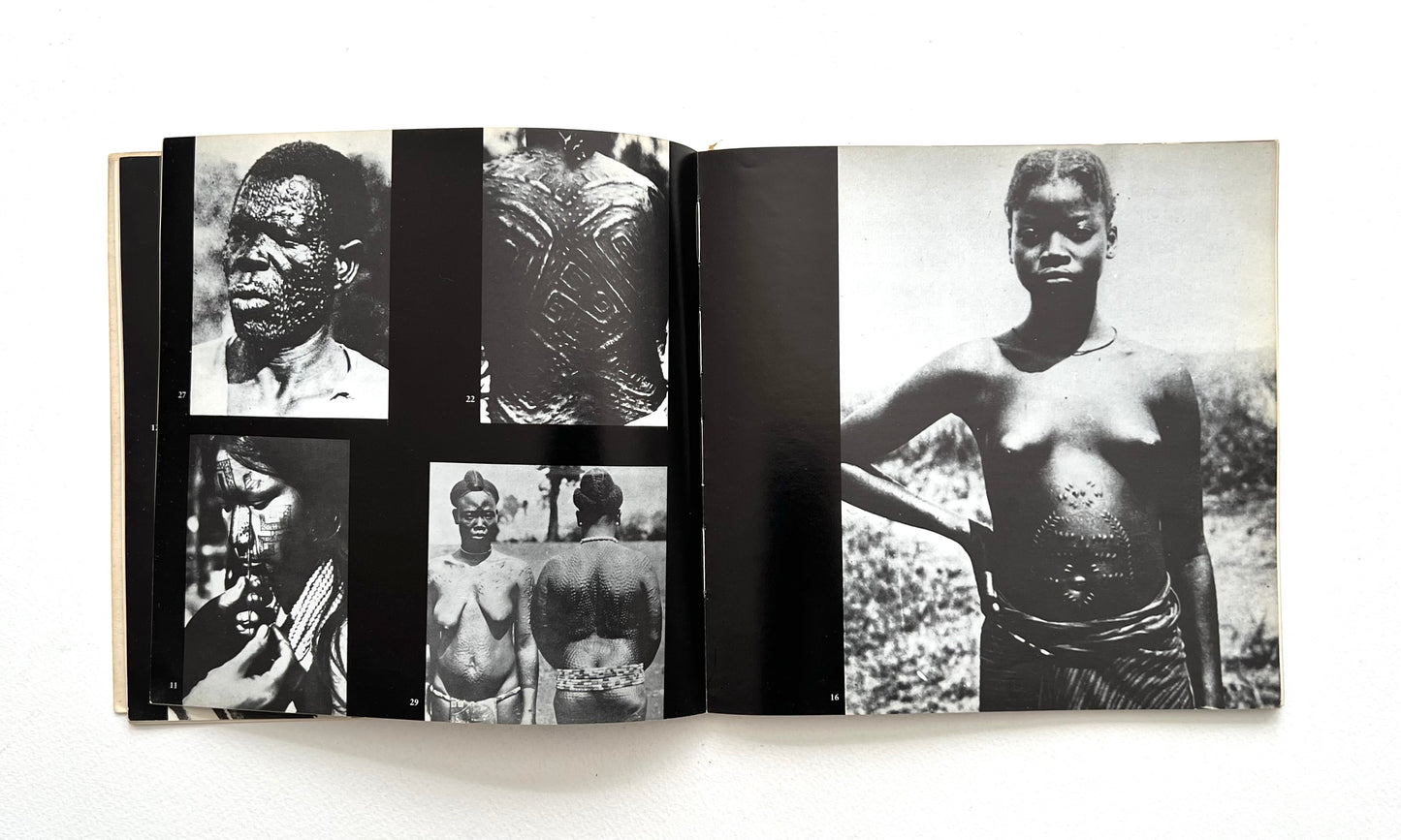 Open book displaying black and white photographs of indogenous people with tattoos on a white background