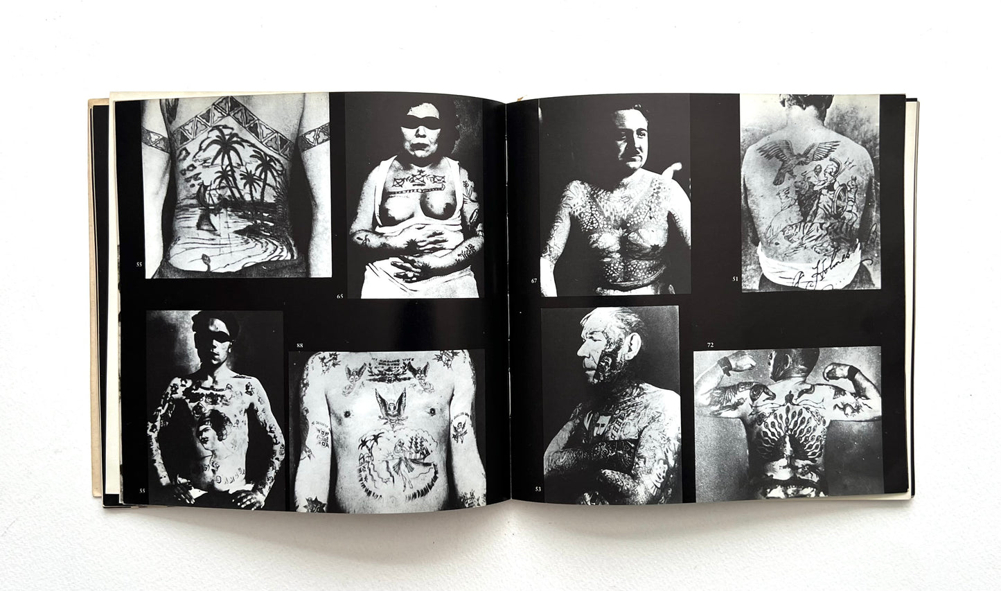 Open book displaying black and white images of tattoos on people's bodies.