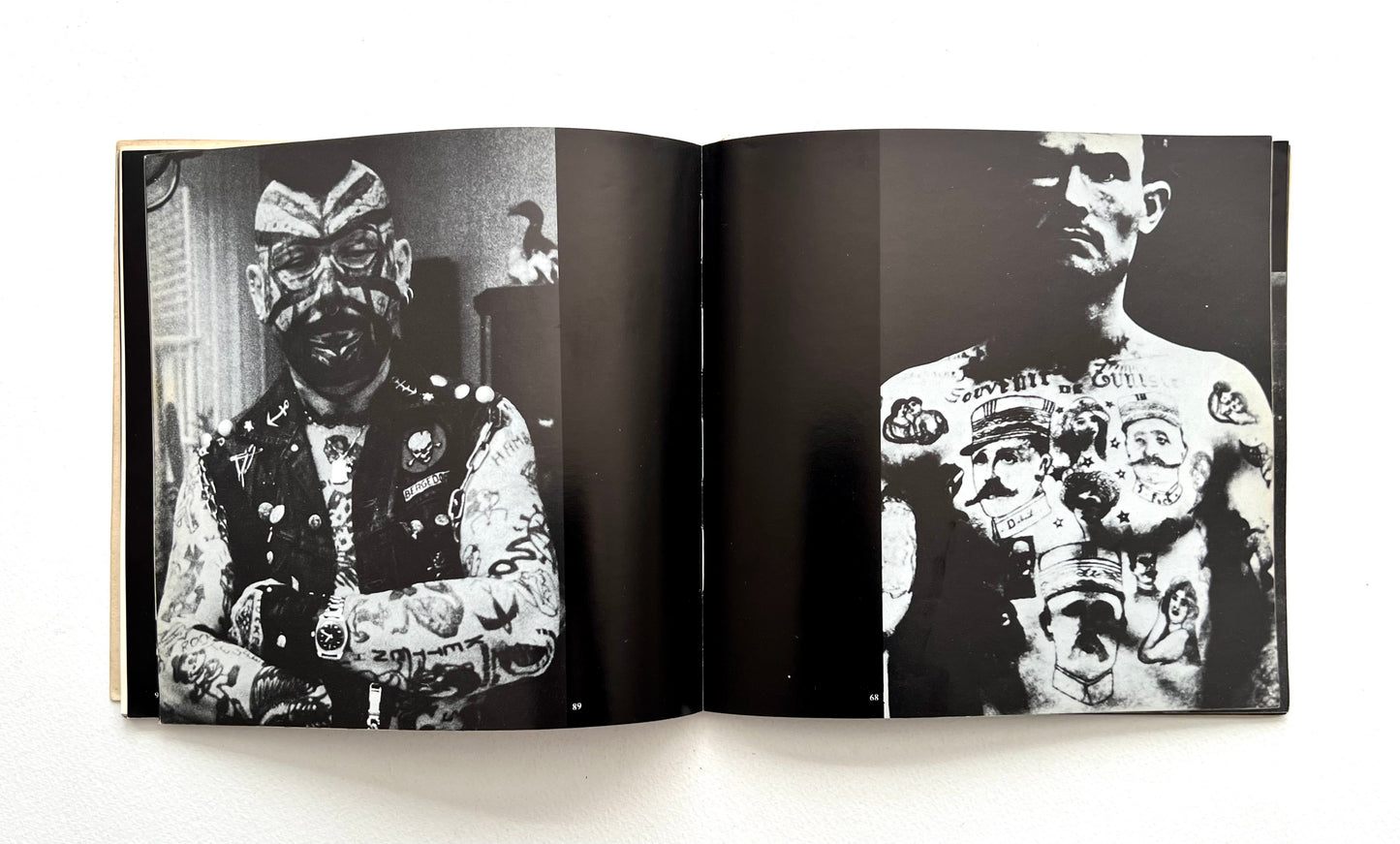 Open book showing black and white images of a person with tattoos on a white background
