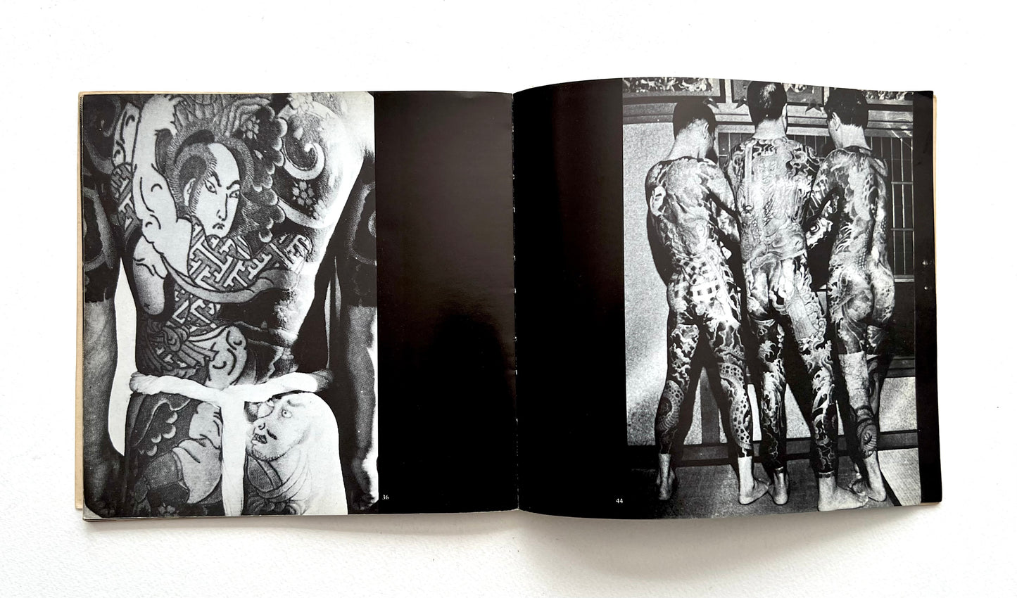 Open book showing black and white images of tattoos on people's backs and legs.