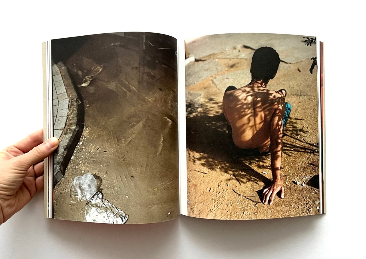 Open book - 'Port Yarin' by Jeff Hahn - showing a photographs of a man sitting on the ground with tree shadows.