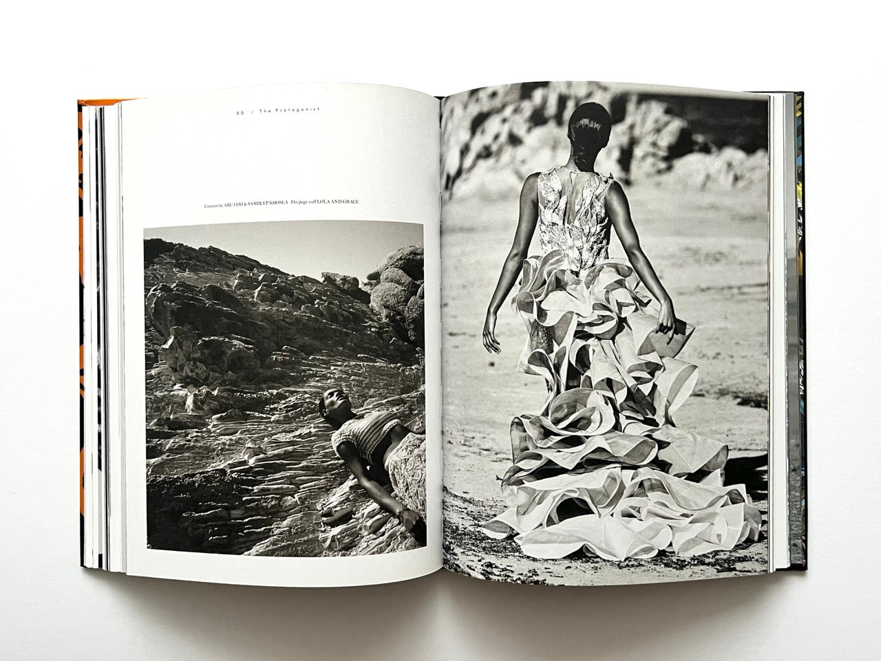 Open book showing black and white fashion photographs of a woman in a dramatic dress on a rocky beach.