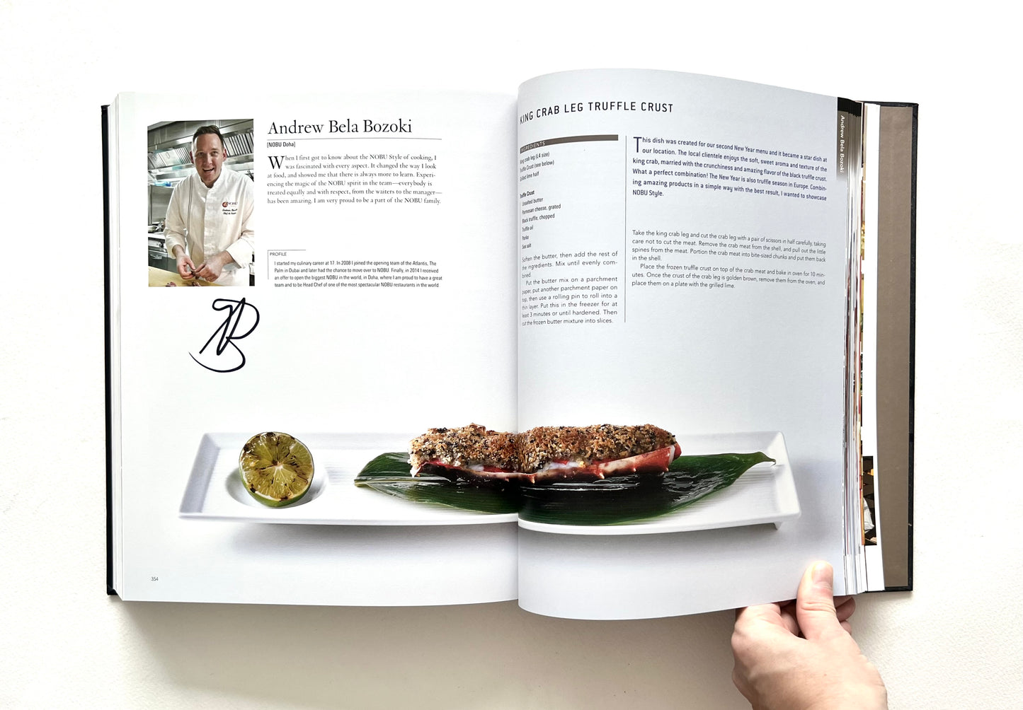 Open "World of Nobu" cookbook showing a recipe and a photo of a KING CRAB LEG TRUFFLE CRUST dish - signed by chef Andrew Bela Bozoki.