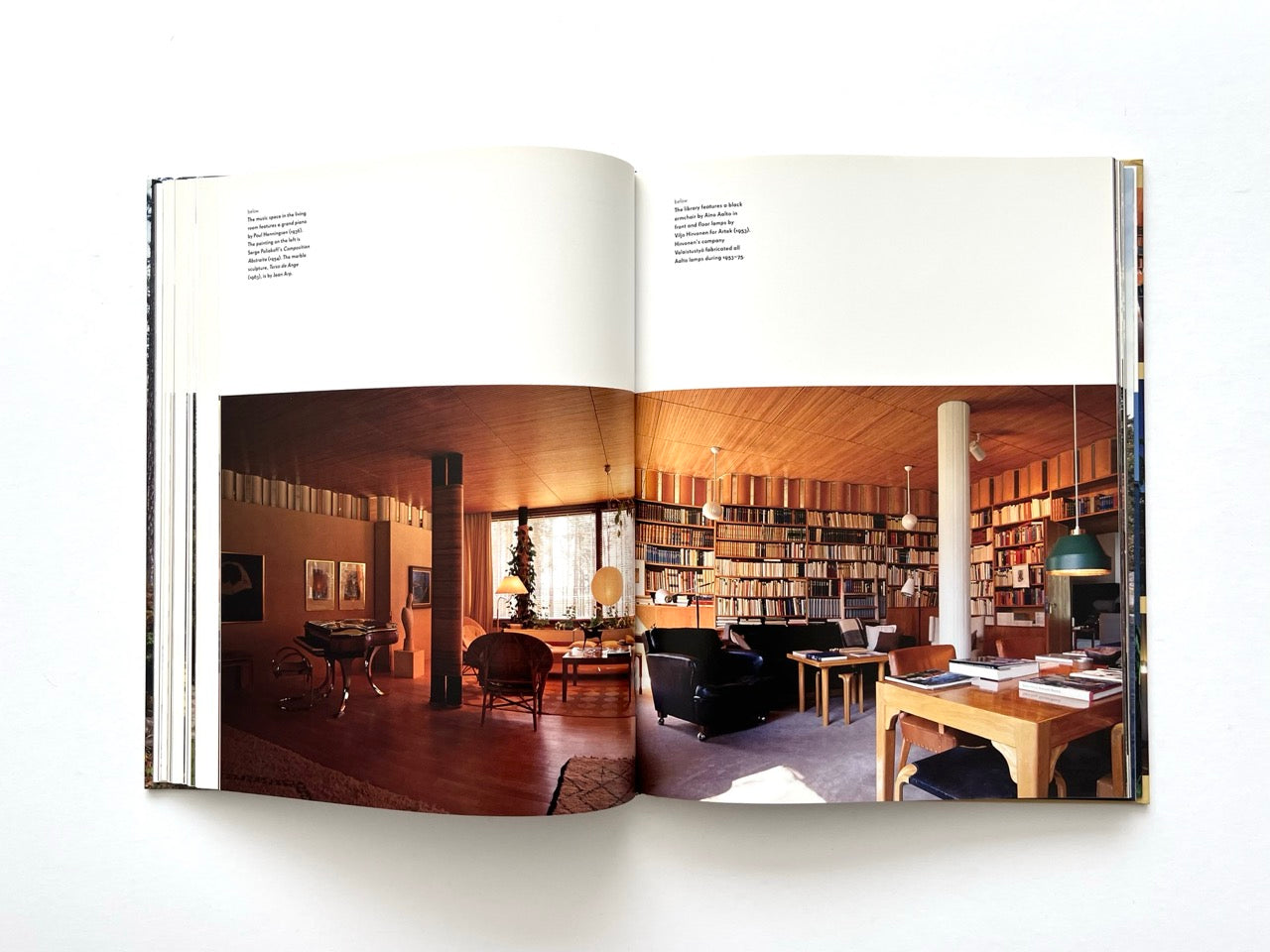 Double-page interior photograph from Alvar Aalto Houses (2011) by Jari Jetsonen and Sirkkaliisa Jetsonen, showing Villa Mairea's library with floor-to-ceiling bookshelves, original Aalto furniture and timber-lined interiors.