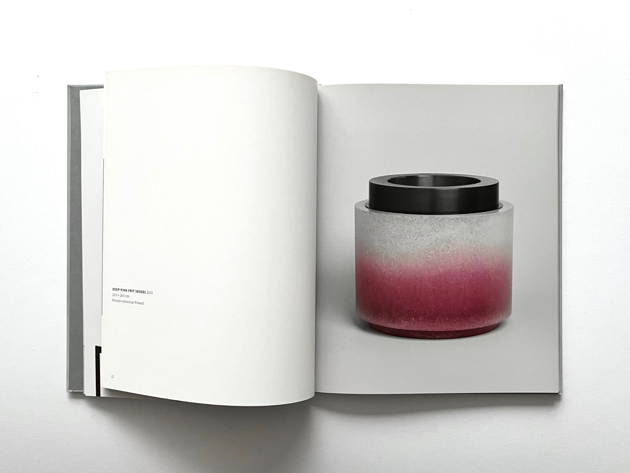 Open spread of the book “Anna Dickinson”, showing a full-page photograph of a cylindrical glass vessel with a frosted grey-to-deep pink gradient and a black rim on the right page, against a neutral grey background.