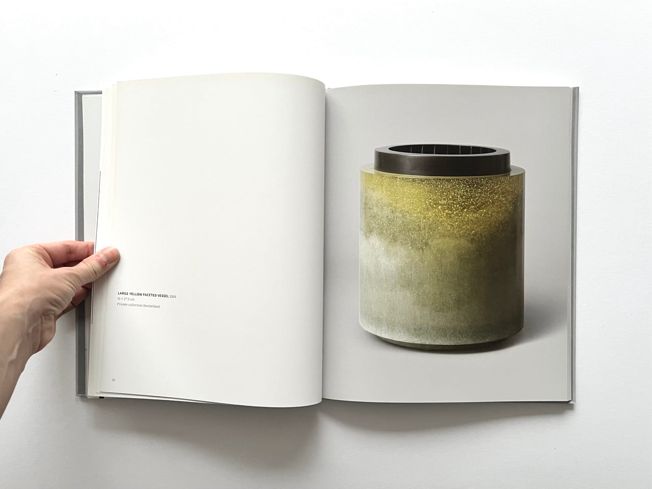 Open spread of the book “Anna Dickinson”, showing a full-page photograph of a large cylindrical glass vessel with a mottled green and gold surface and dark rim on the right page, against a neutral grey background.