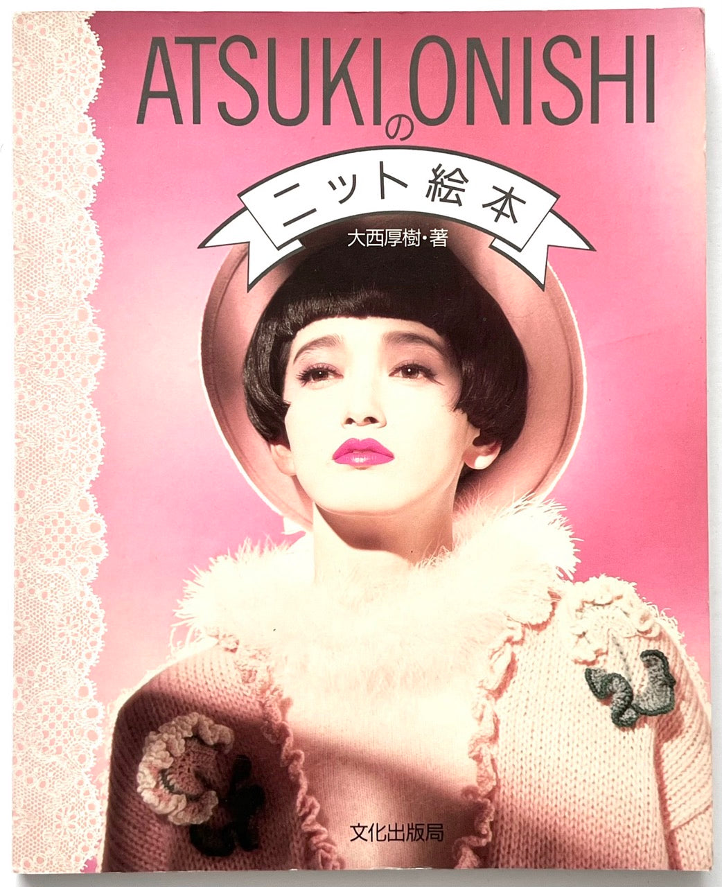 Front cover of Atsuki Onishi no Knit Ehon (Atsuki Onishi's Knit Picture Book) by Atsuki Onishi, published in 1989, featuring a fashion portrait of a model wearing a pink knit sweater with appliqué details, a white fur collar and a pink hat against a vivid pink background.