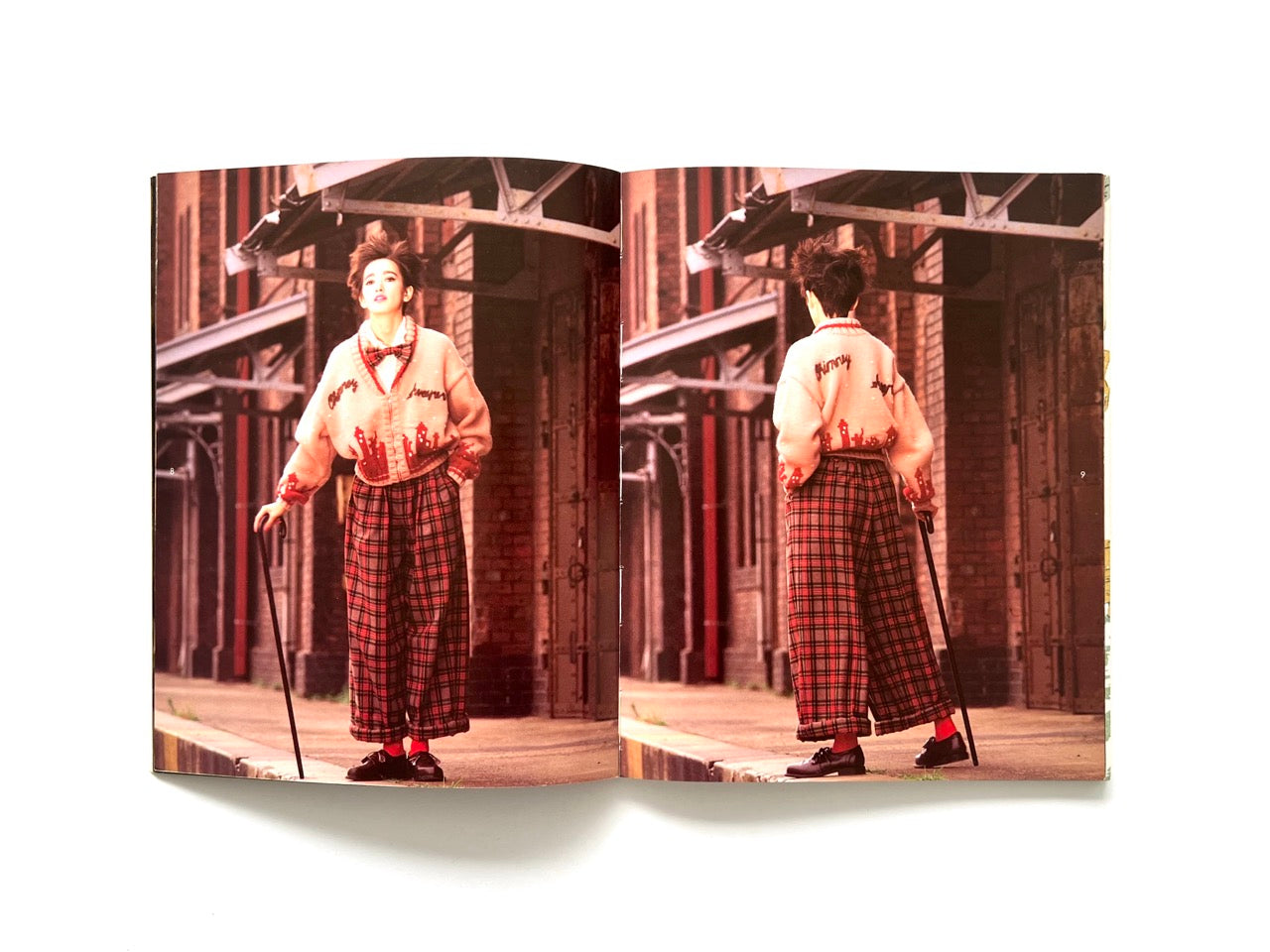 Interior spread from Atsuki Onishi's Knit Picture Book, published in 1989, showing front and back views of a model wearing a pastel pink knit cardigan and wide tartan trousers in an industrial setting.