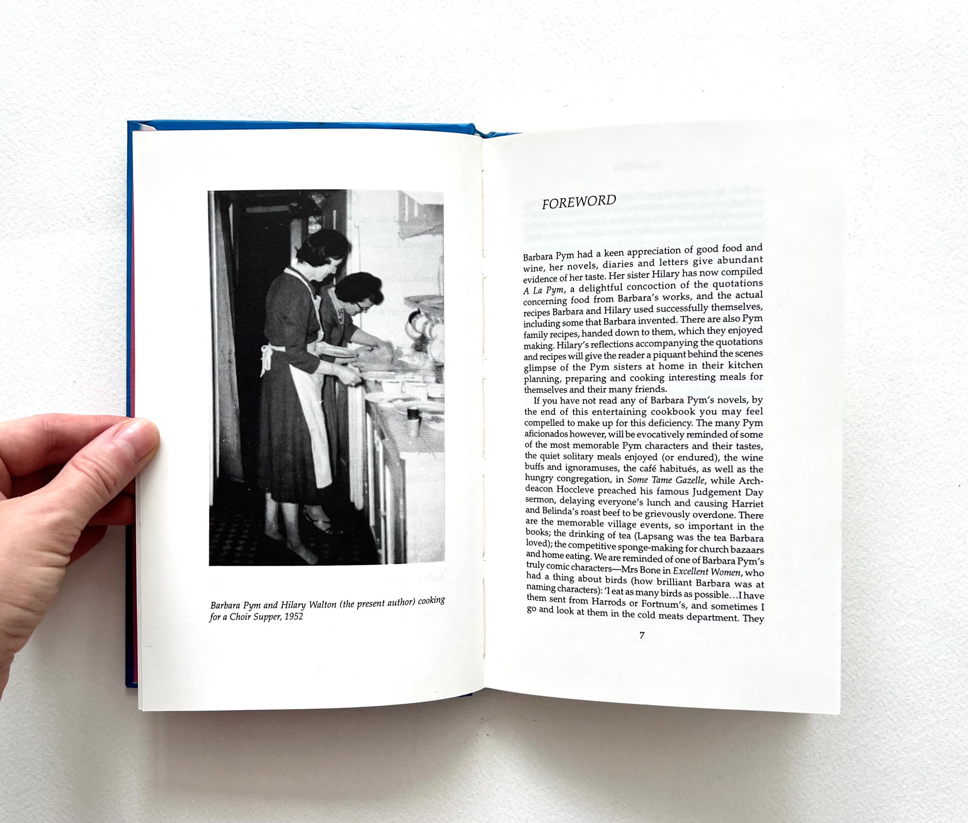 Open book with a black and white photo  of Barbara Pym and Hilary Pam cooking, on the left page and text on the right page.
