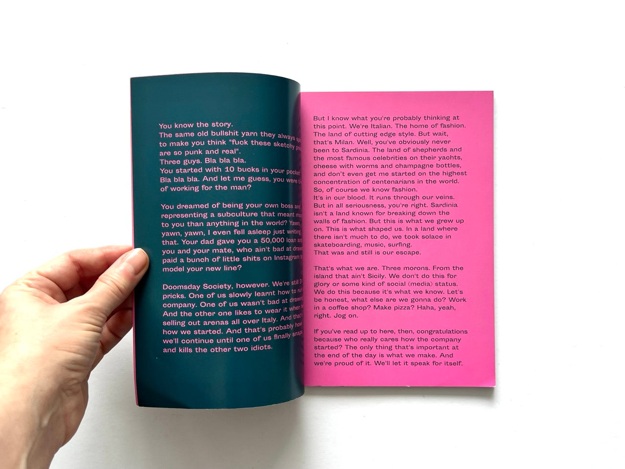 Doomsday Society Issue No. 01 – Interior spread with manifesto-style text in white across contrasting teal and pink pages discussing the brand’s origins and ethos.