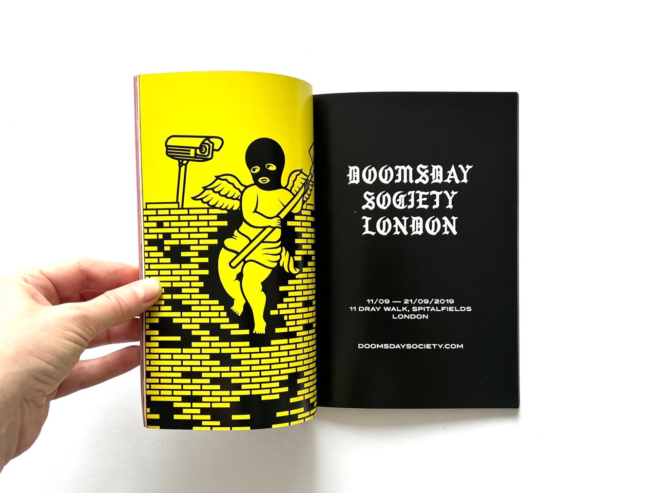 Doomsday Society Issue No. 01 – Interior spread with graphic illustration of masked winged figure on yellow page and opposite event details for Doomsday Society London.