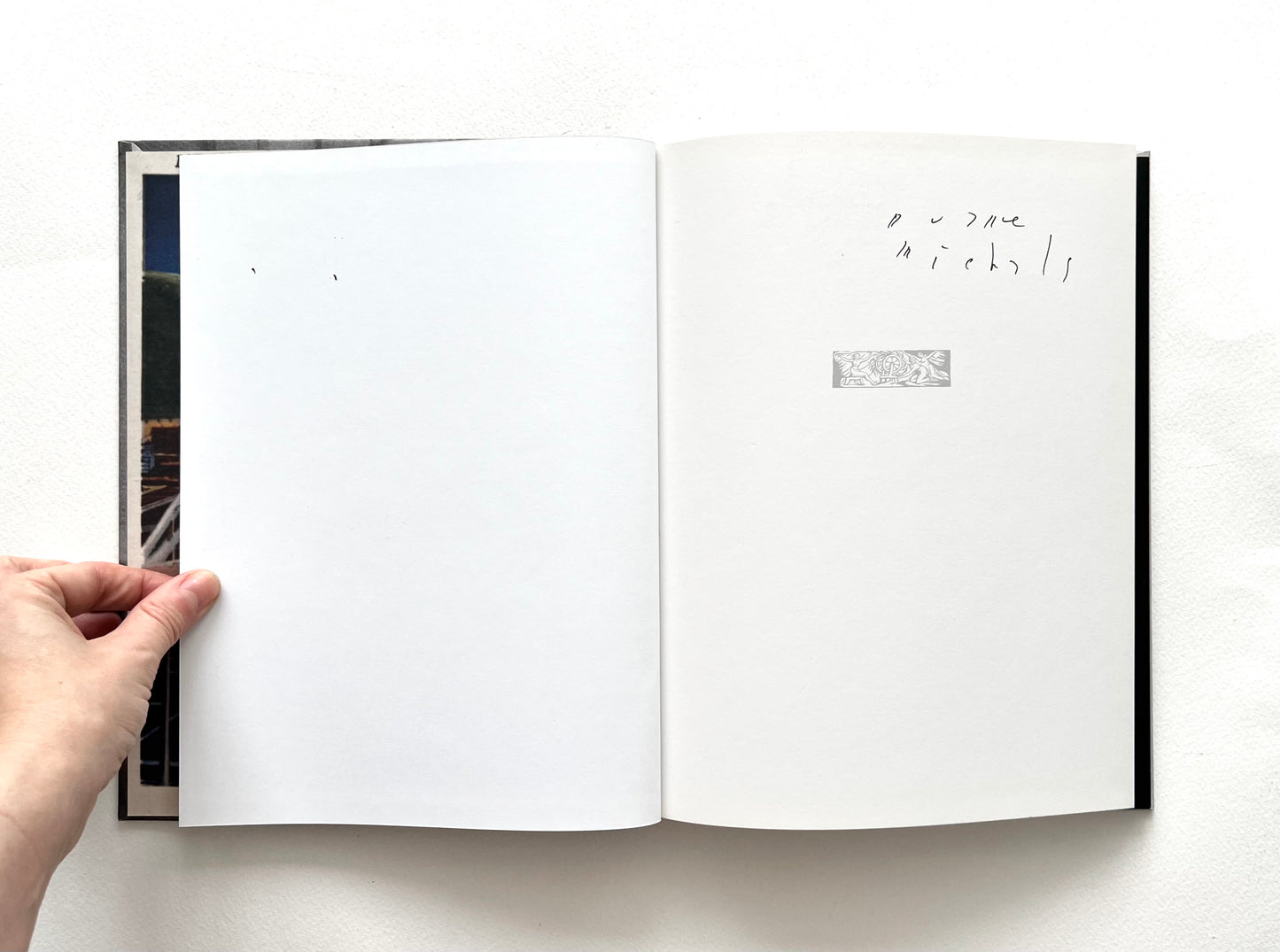 Open book autographed by Duane Michals, with a hand holding it on a white background