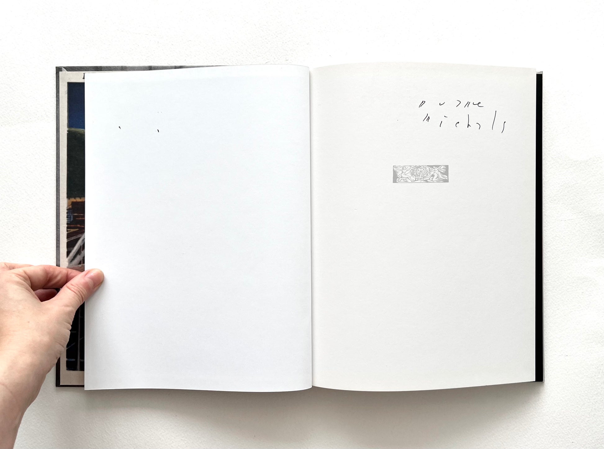 Open book autographed by Duane Michals, with a hand holding it on a white background