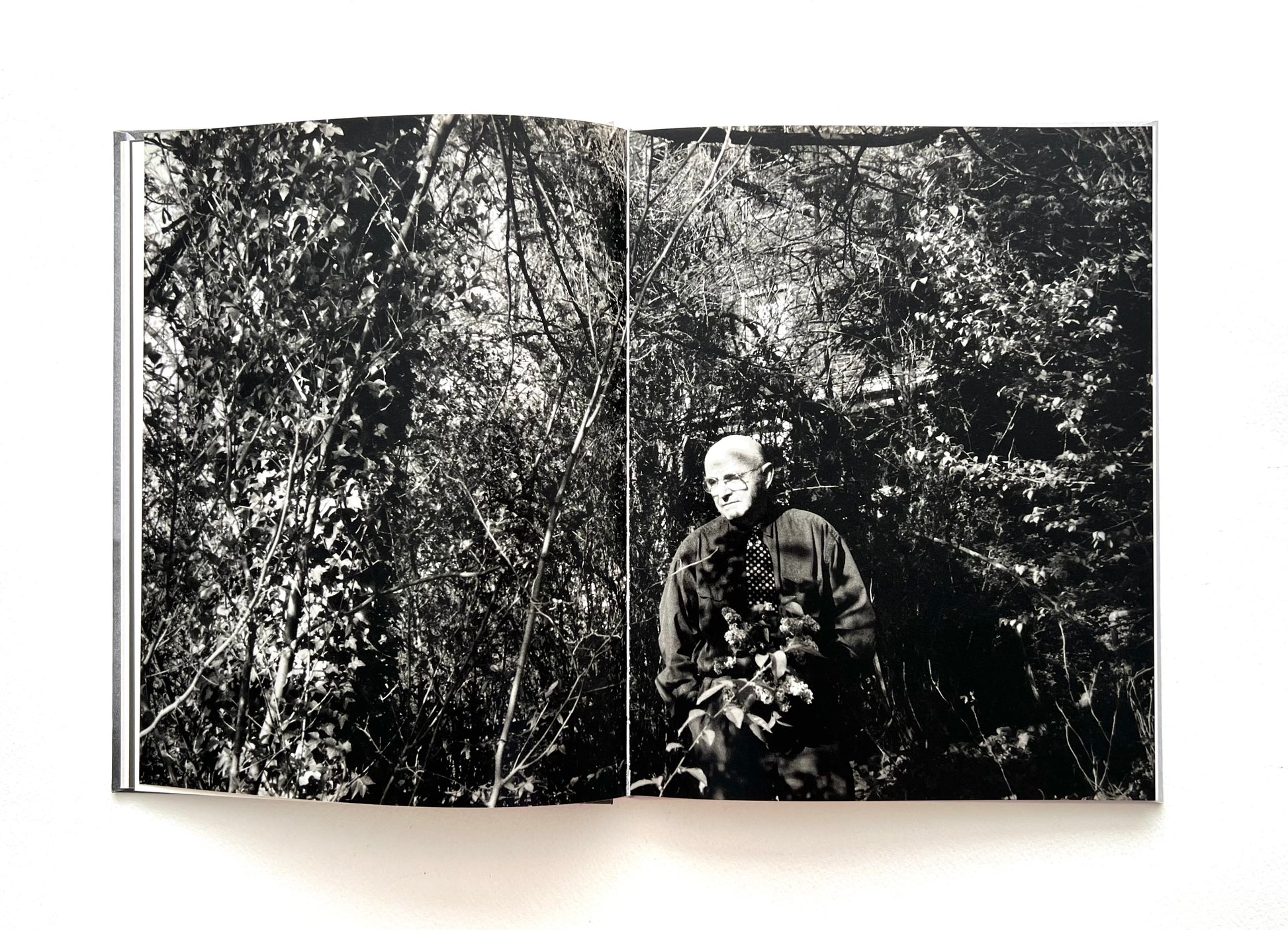 Open book showing a black and white photograph of DUANE MICHALS in a forest.
