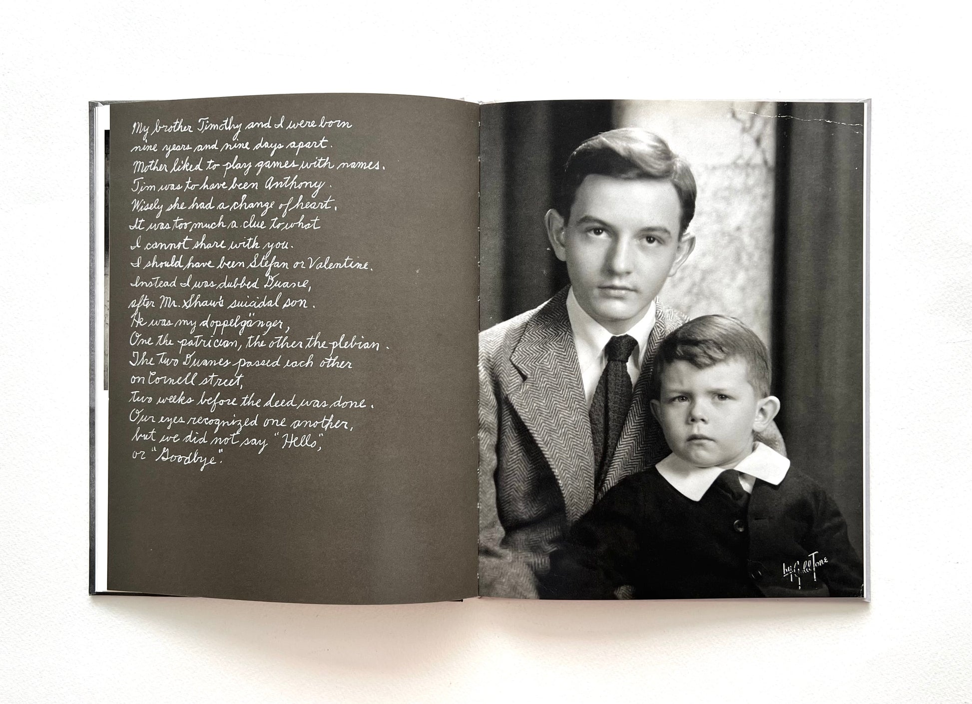 Open book with a vintage black and white portrait photograph of two boys and hand-written text by Duane Michalst on a white background