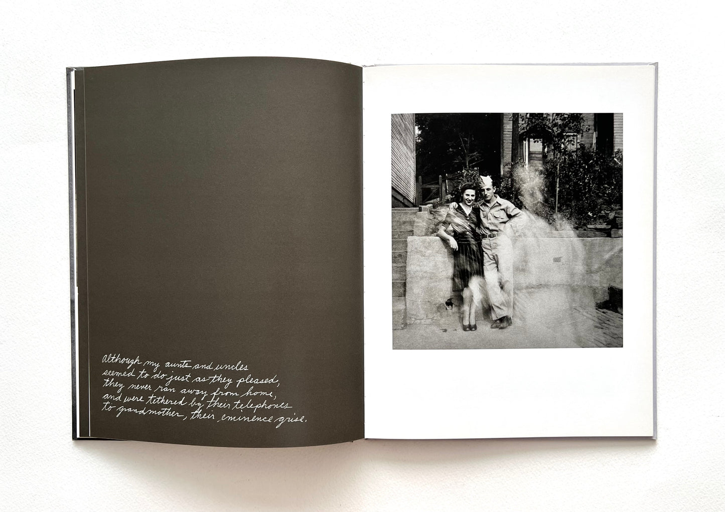Open book with a black and white photograph and hand-written text by Duane Michals on a white background
