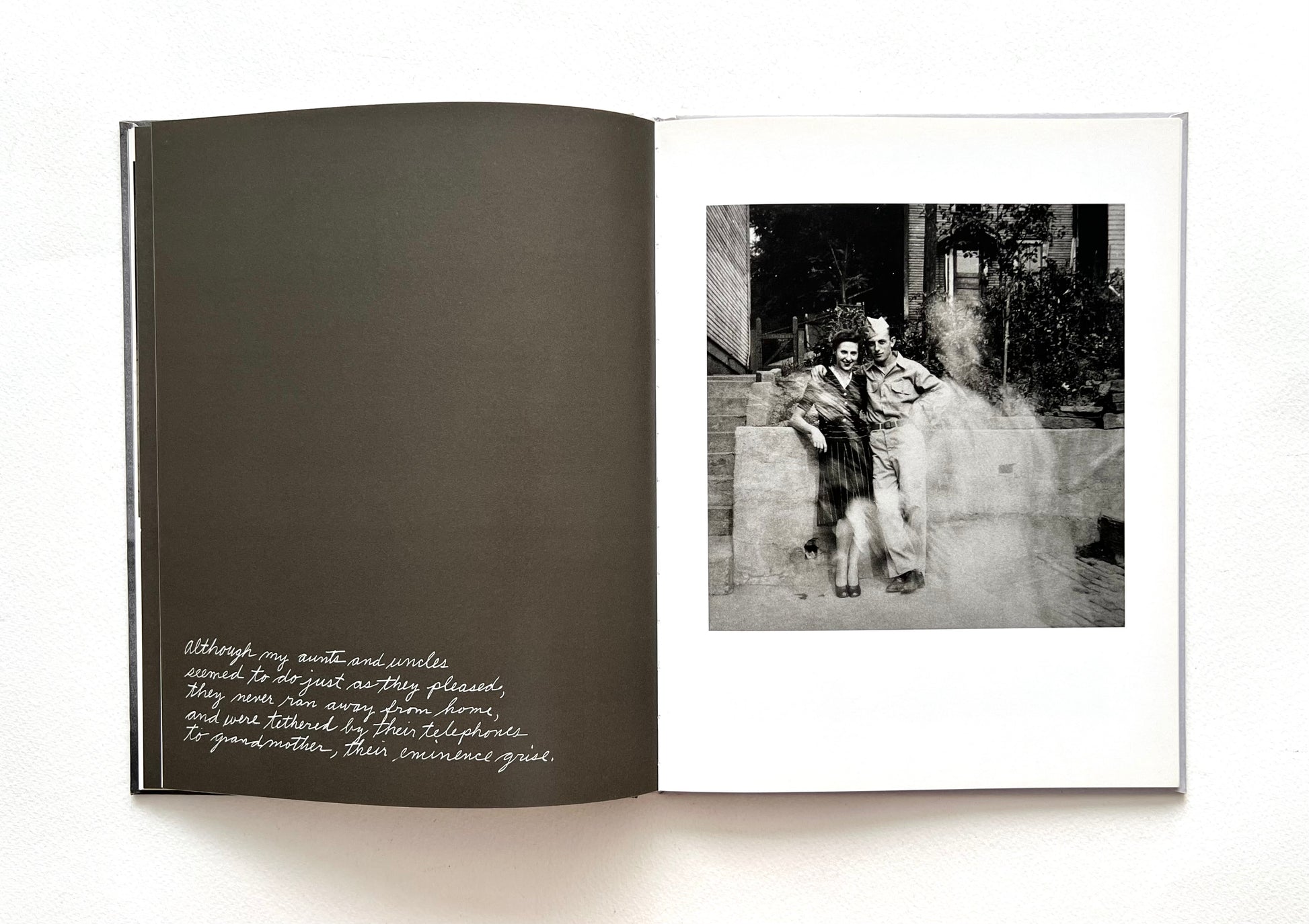 Open book with a black and white photograph and hand-written text by Duane Michals on a white background