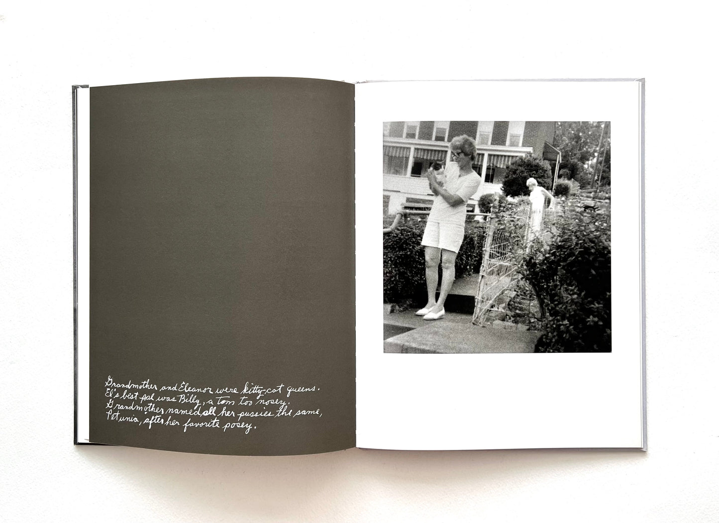 Open book with a black and white photograph of a garden and a woman holding a kitten by DUANE MICHALS.