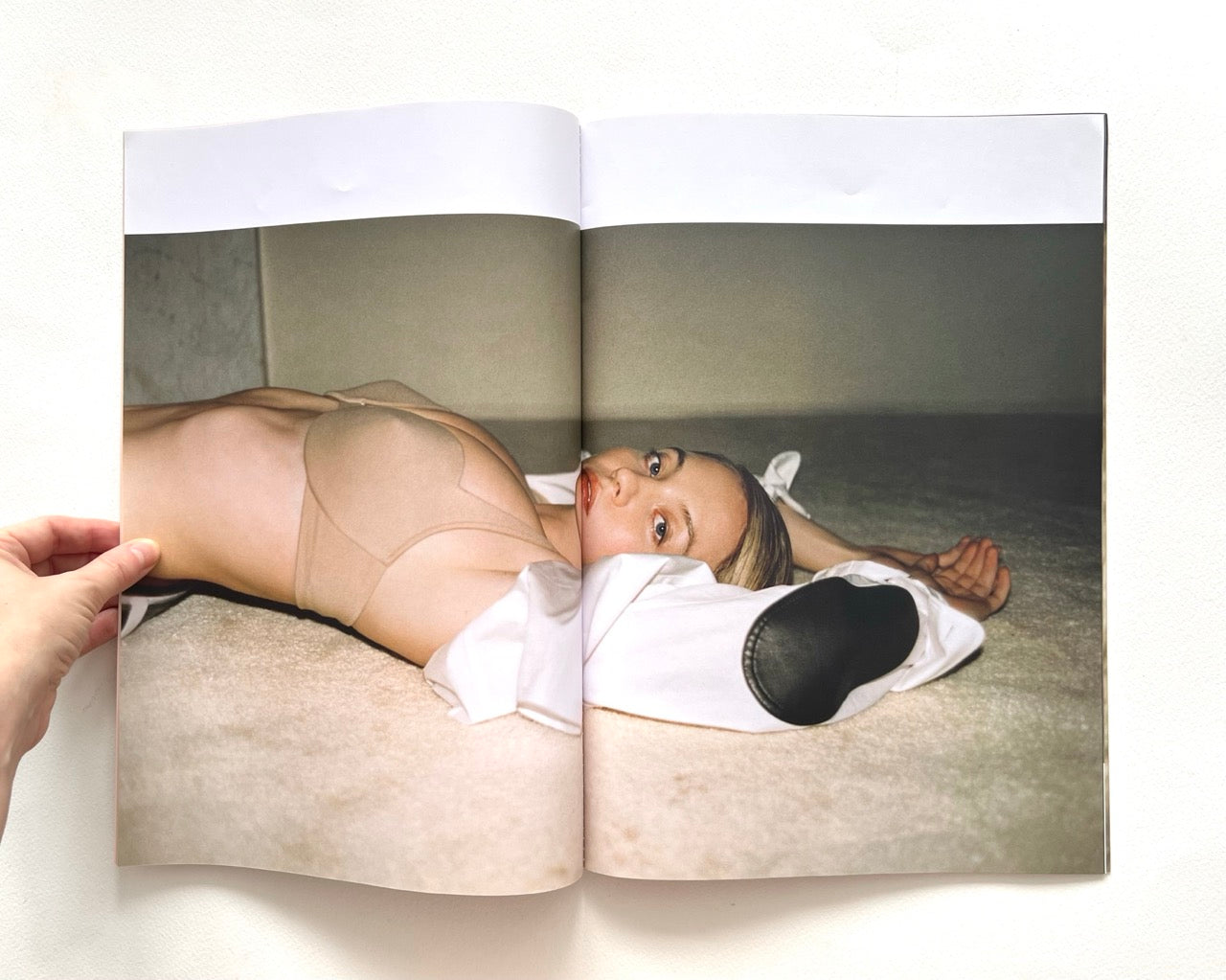 Open magazine showing Sydney Sweeney lying on a bed with a neutral background