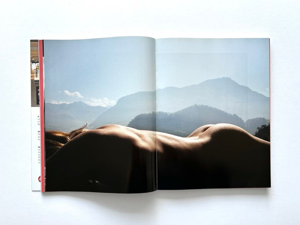 FOAM International Photography Magazine, Issue #35: Lust, Summer 2013. Full-bleed double-page colour photograph featuring the reclining nude body of a woman silhouetted against a hazy mountain landscape and pale blue sky.