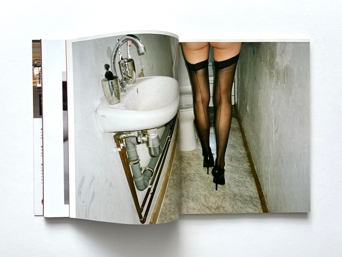 FOAM International Photography Magazine, Issue #35: Lust, Summer 2013. Full-bleed colour photograph spanning two pages, depicting a woman wearing black stockings and high heels in a narrow bathroom with a white sink and exposed plumbing.
