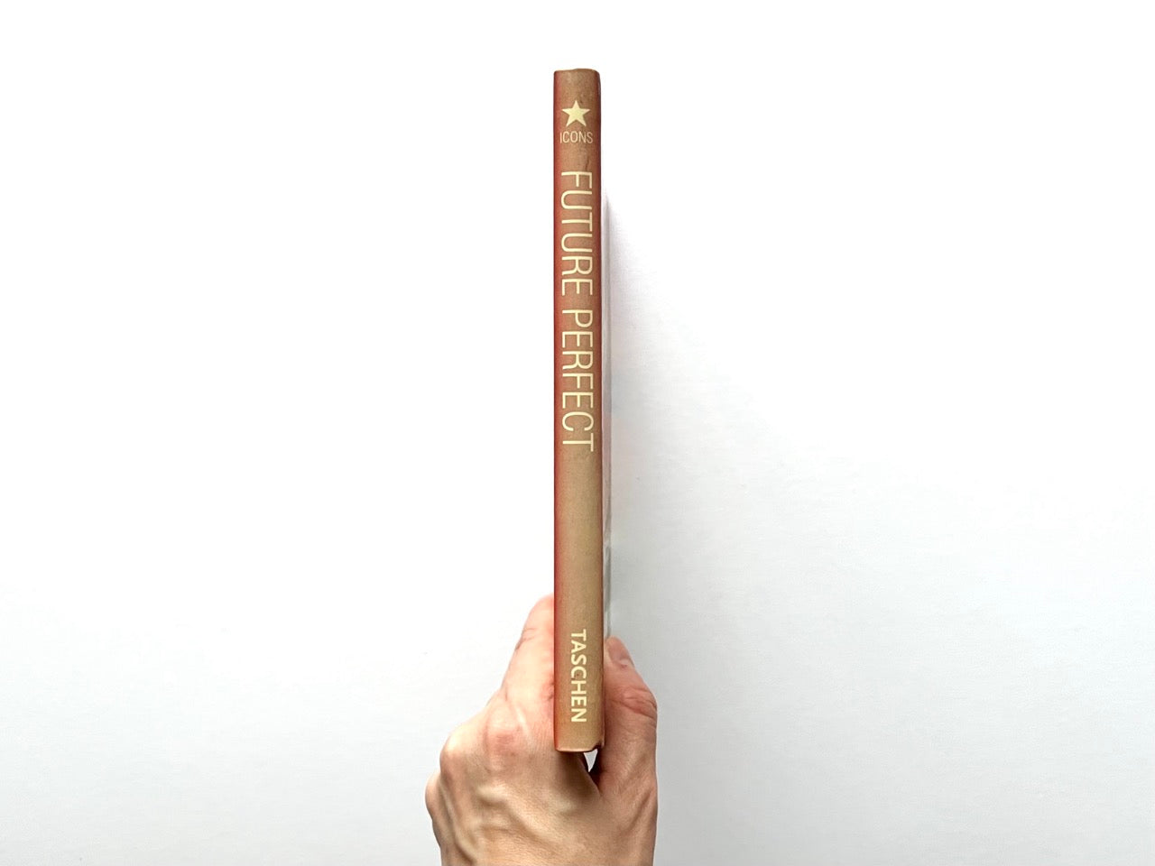 Spine of “Future Perfect: Vintage Futuristic Graphics,” showing the title and Taschen branding, held upright against a white background.