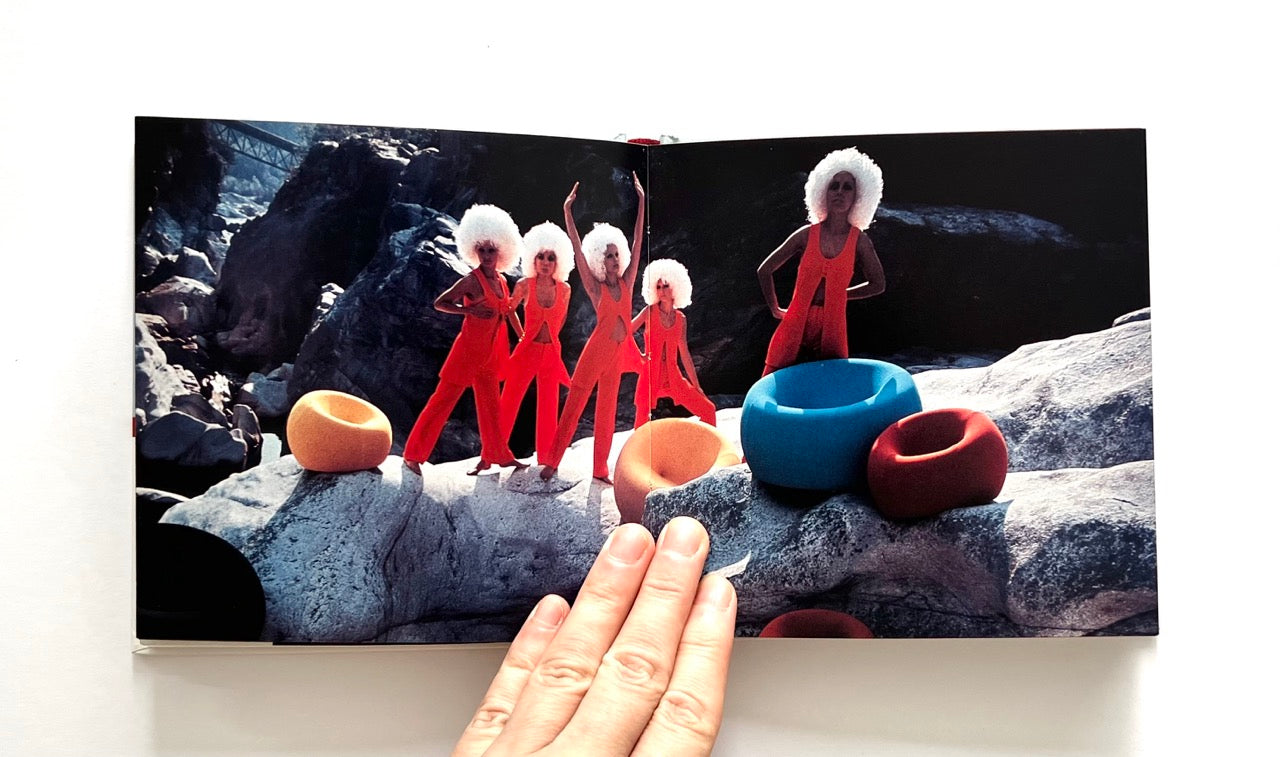 Open book - GAETANO PESCE
by Marisa Bartolucci - showing a scene with figures in red suits and colorful bowls on a rocky surface.