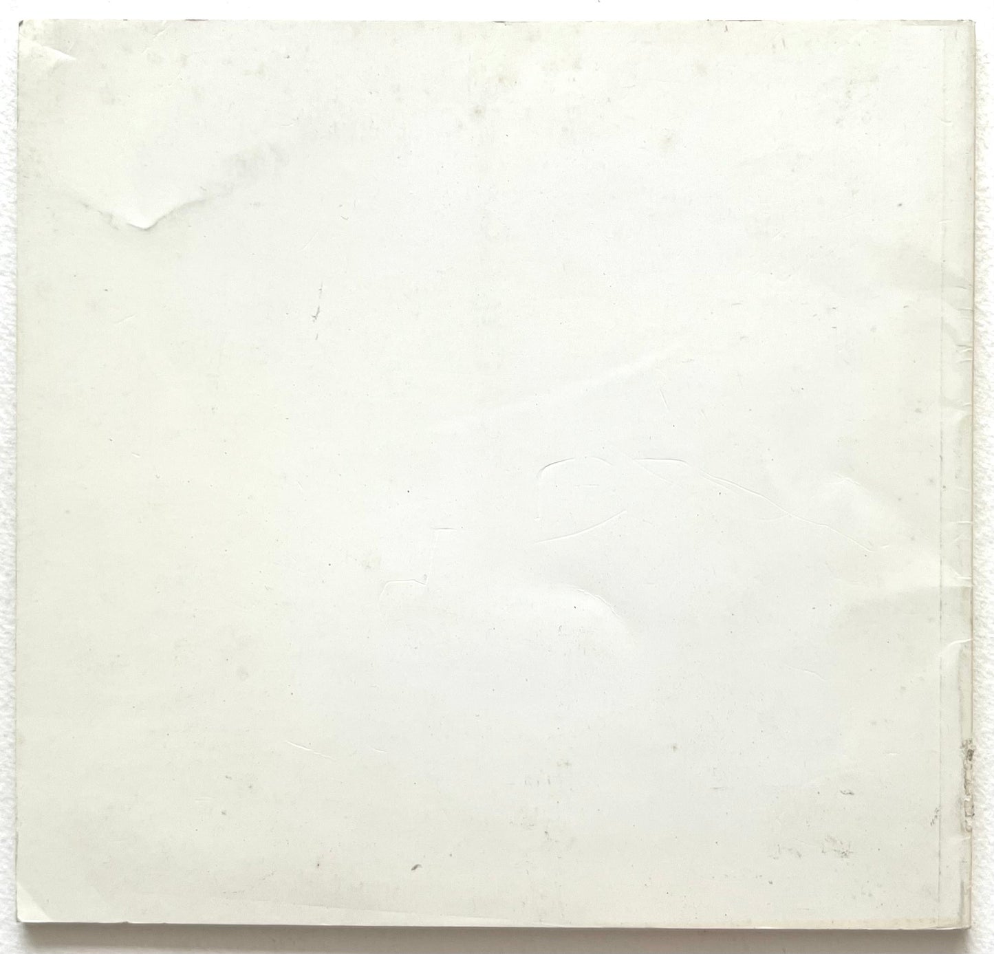 Plain white rear bookcover with slight rubbing and age-tanning.