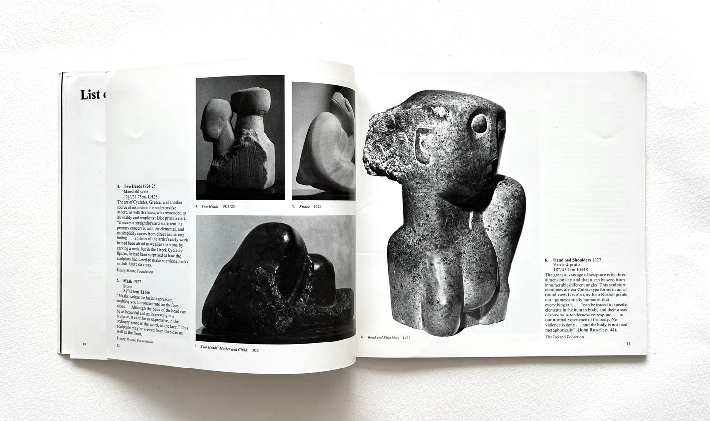 Open book showing black and white photographs of Henry Moore's stone sculptures on a white background