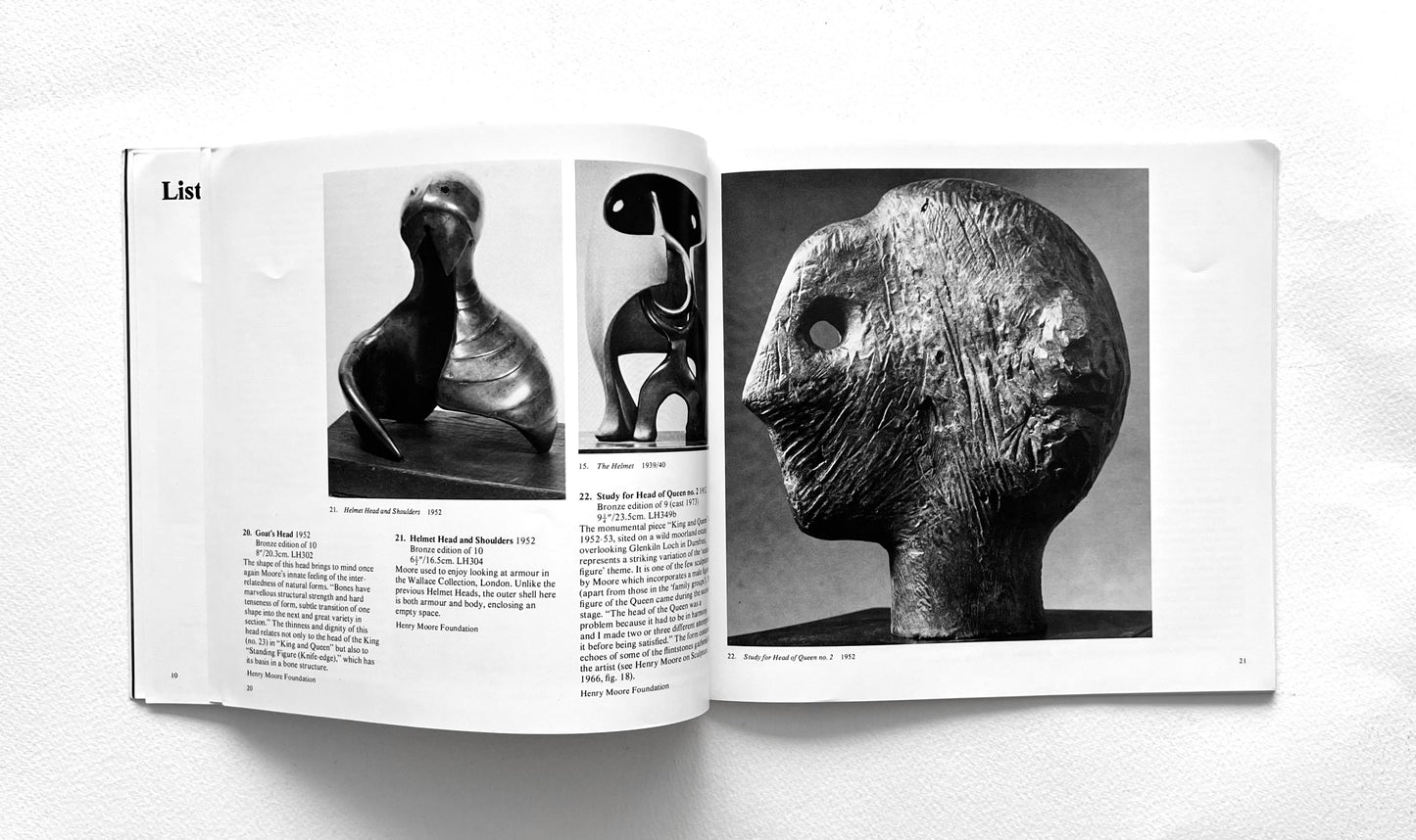Open book showing black and white photographs of Henry Moore's head sculptures on a white background