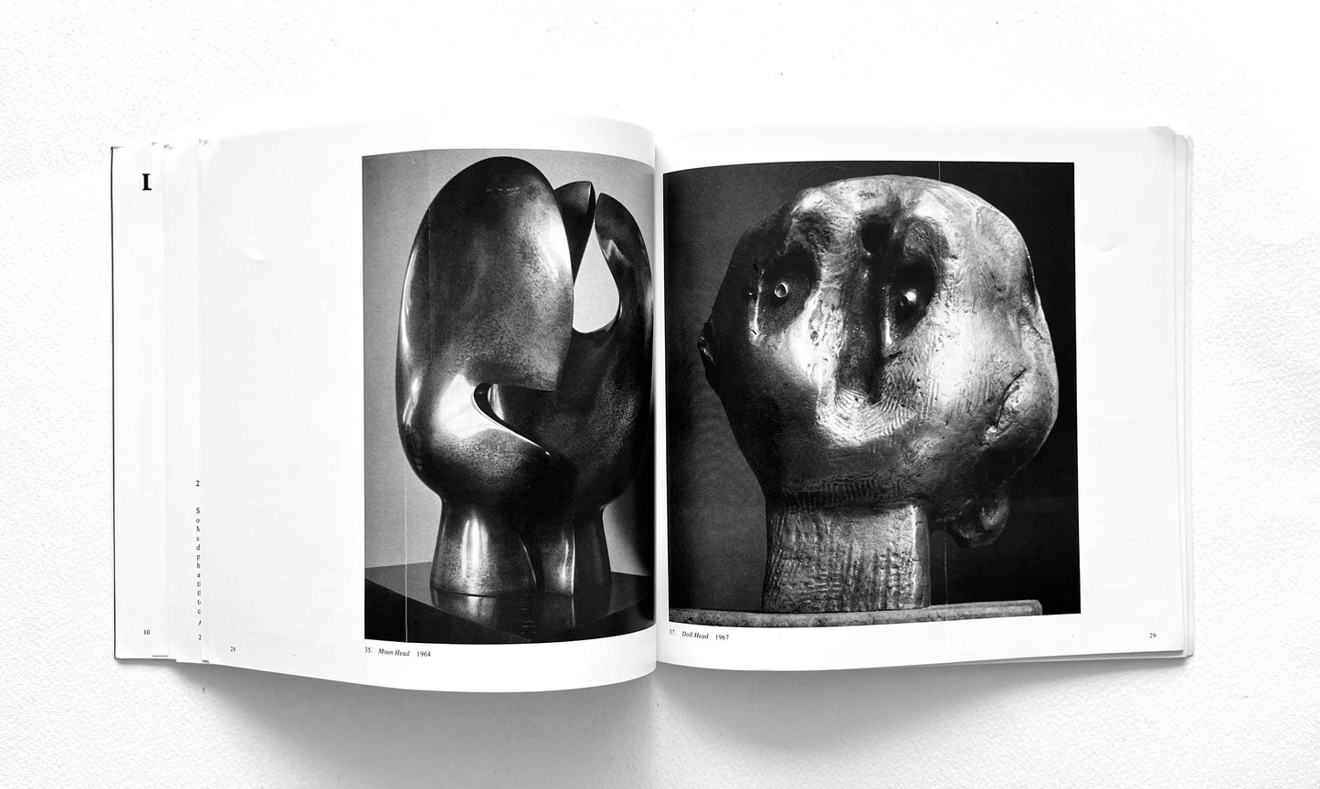 Open book displaying black and white photographs of Henry Moore's head sculptures on a white background
