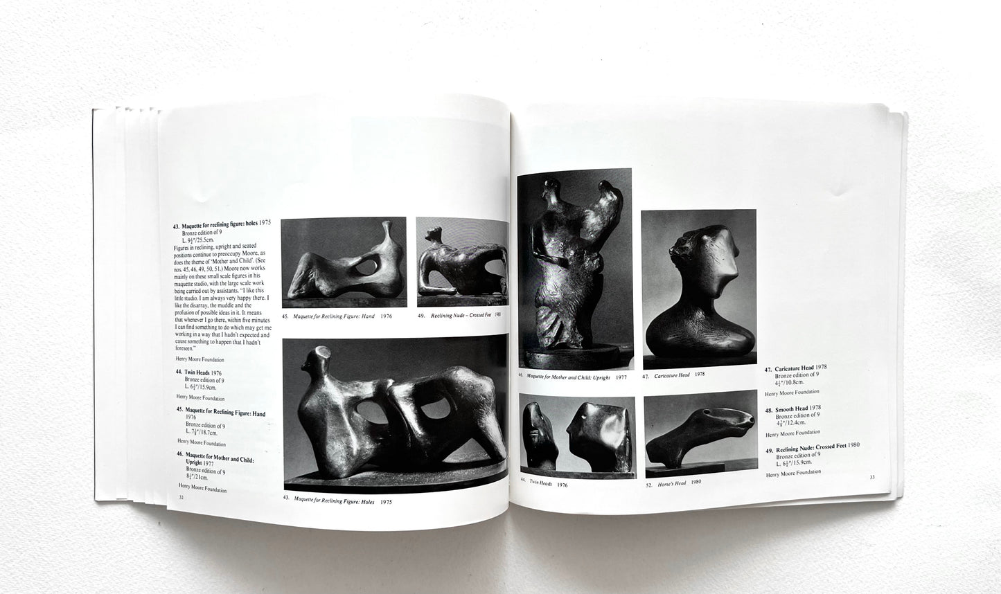 Open book showing black and white photographs of Henry Moore's sculptures on a white background