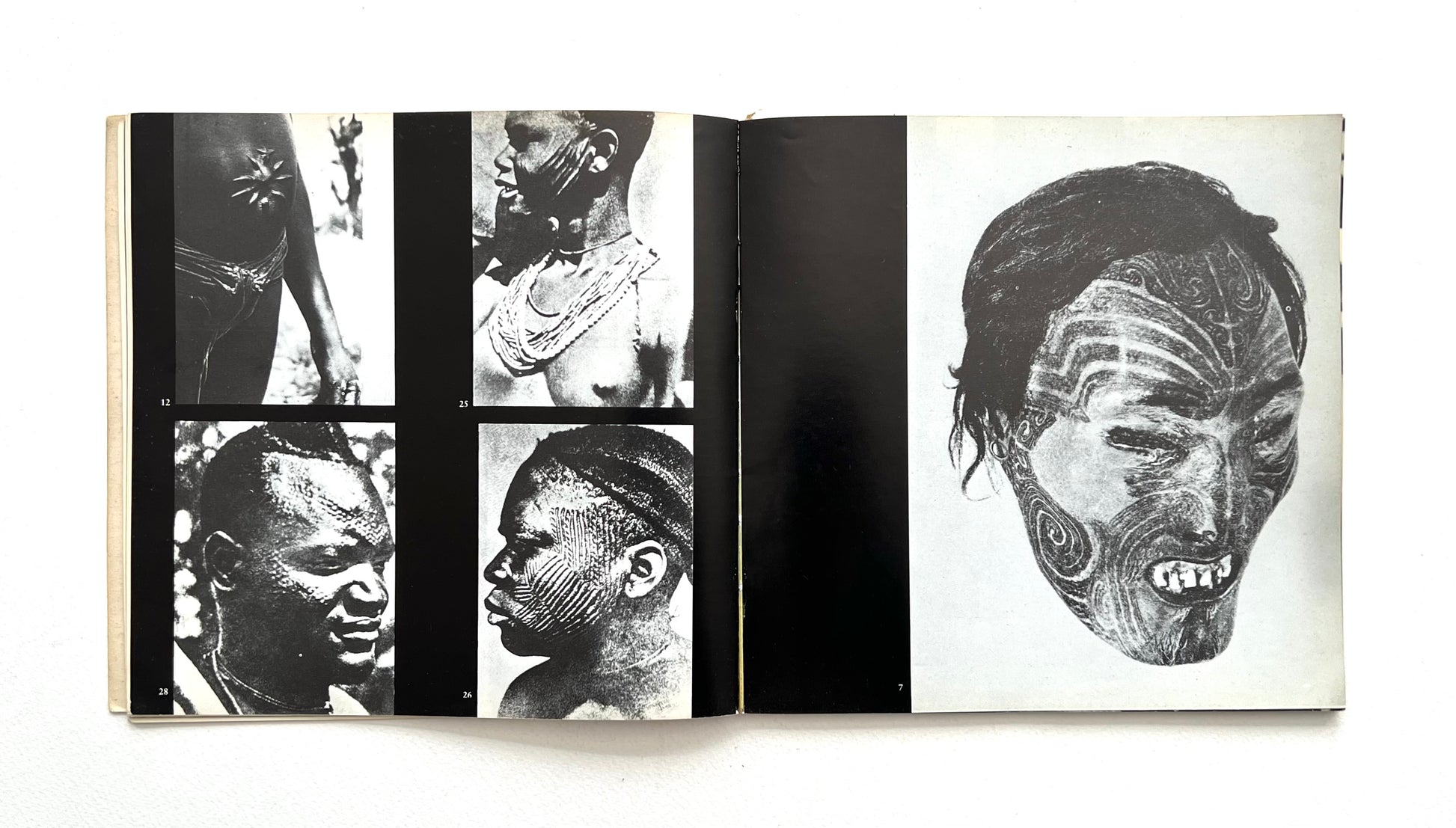 Open book showing black and white images of faces with tattoos