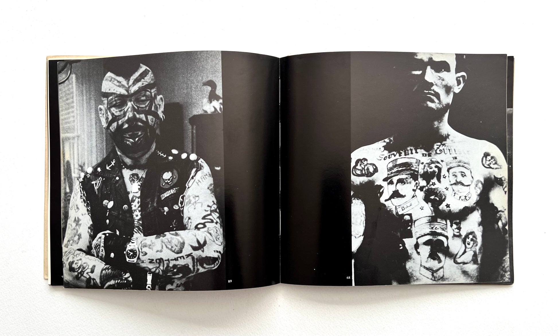 Open book showing black and white images of a person with tattoos on a white background
