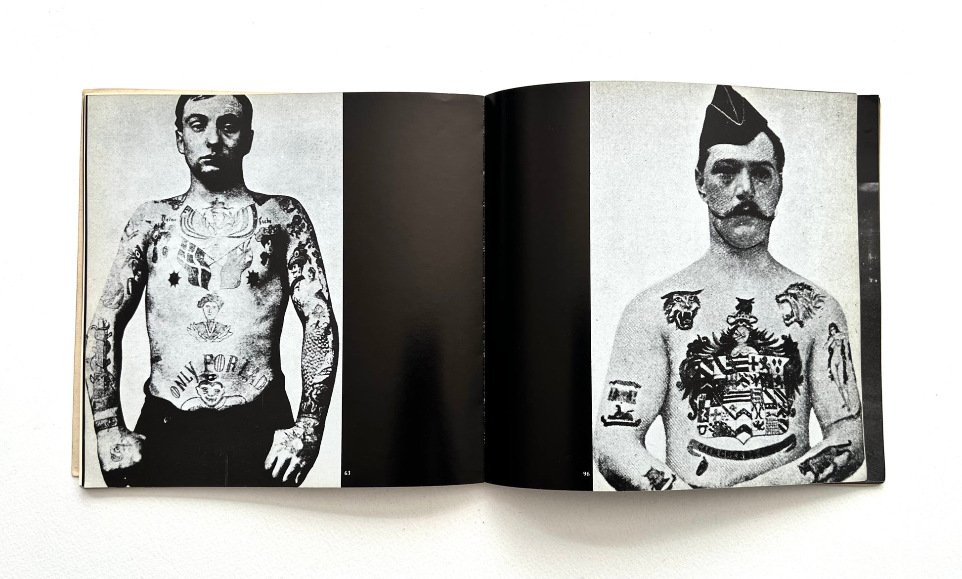 Open book showing black and white photographs of men with tattoos on a white background