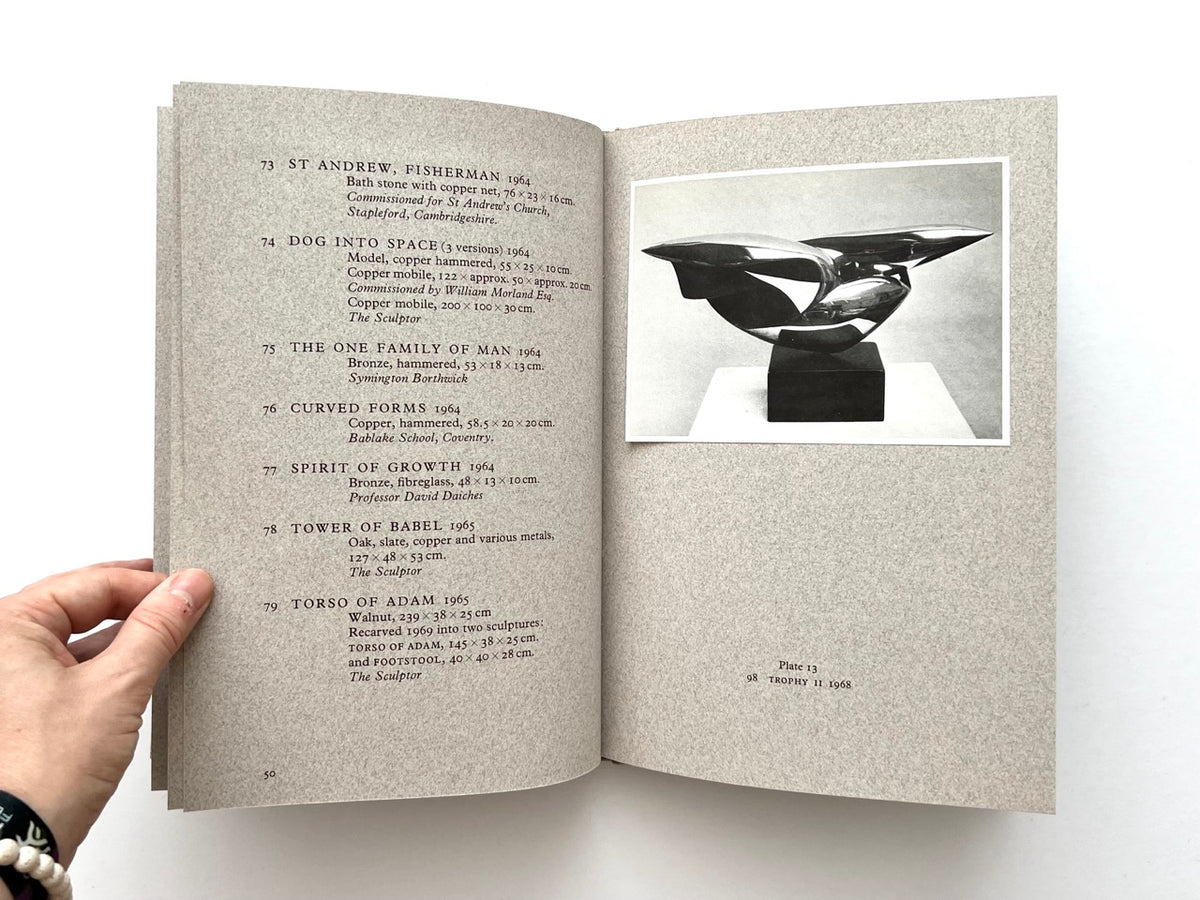 John Skelton: A Sculptor’s Work 1950–1975 (1977). Interior spread showing catalogue entries 73–79 on the left, including St Andrew, Fisherman, Dog into Space, The One Family of Man, Curved Forms, Spirit of Growth, Tower of Babel and Torso of Adam, with Plate 13 on the right featuring a black-and-white photograph of Trophy II (1968).