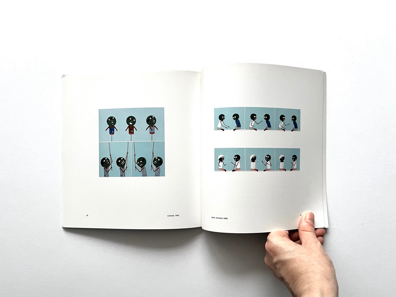 Open spread of the book “Laylah Ali”, showing two grids of small figurative painting reproductions with stylised human figures interacting against pale blue backgrounds, held open by hands against a white background.