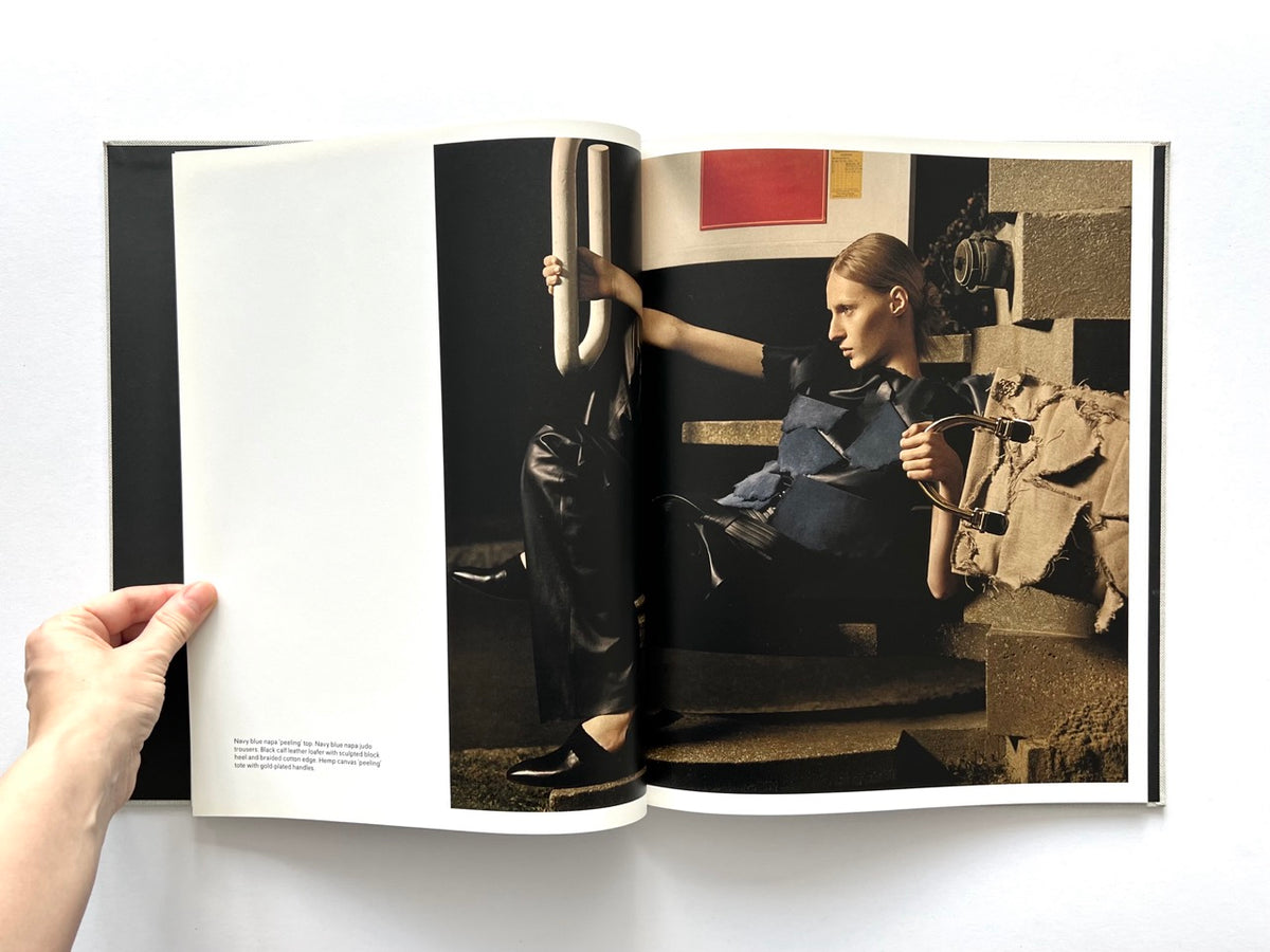 LOEWE Spring Summer 2015 Womenswear, photography by Jamie Hawkesworth, published 2015. Double-page colour photograph of Julia Nobis wearing sculptural navy and black clothing in an industrial setting.