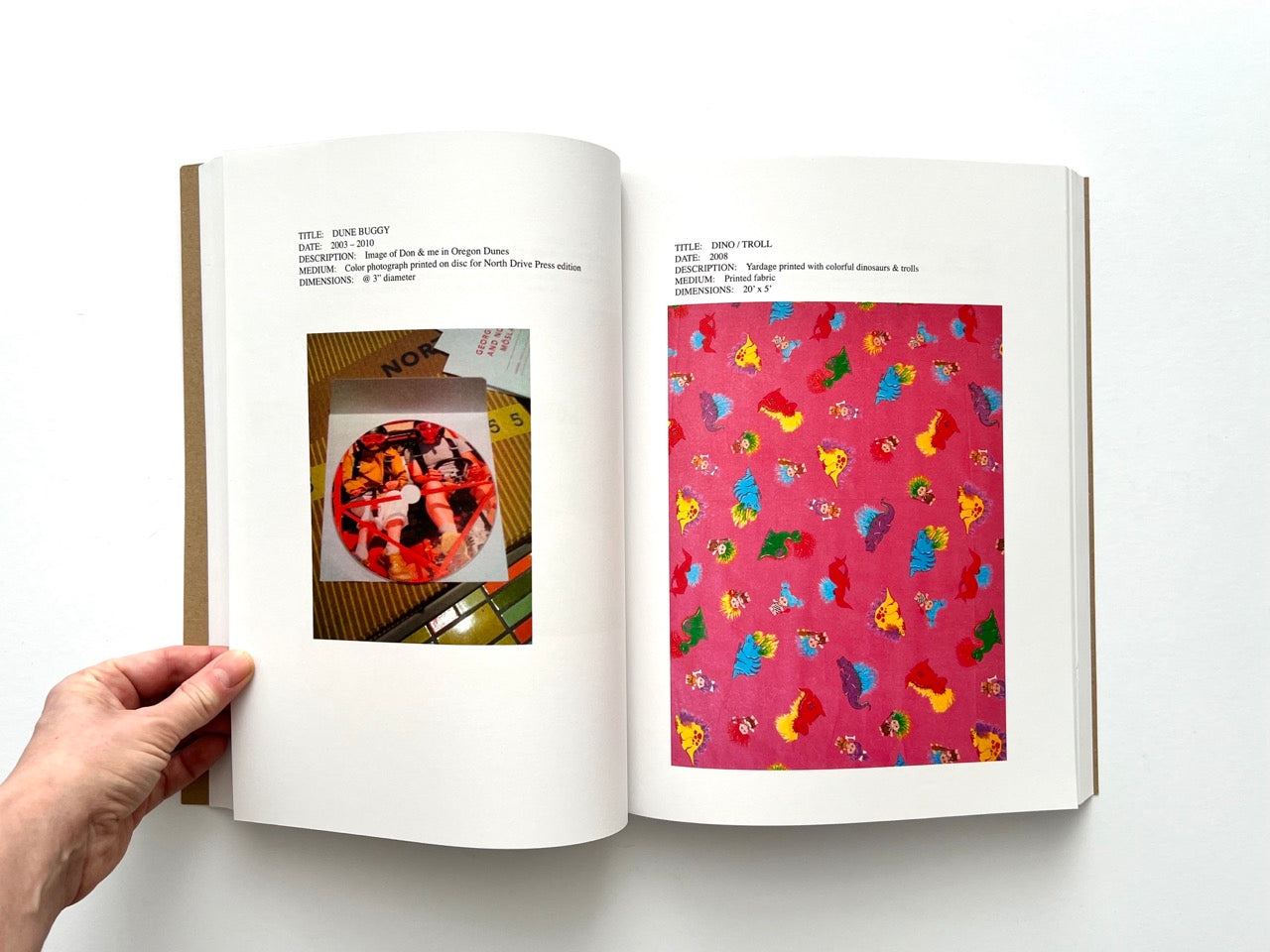 Lutz Bacher: Snow (2013), interior spread showing “Dune Buggy” disc photograph and “Dino / Troll” fabric work with bright multicoloured cartoon figures on pink ground