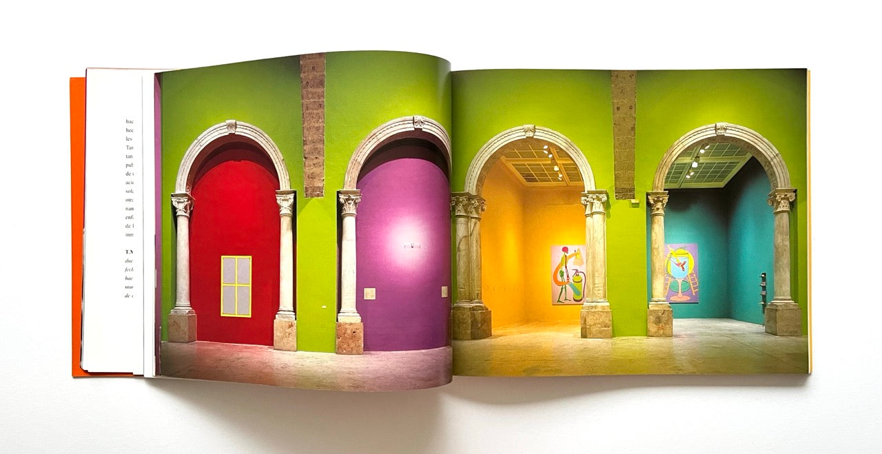 Open book showing a colorful gallery interior with arches and vibrant walls.