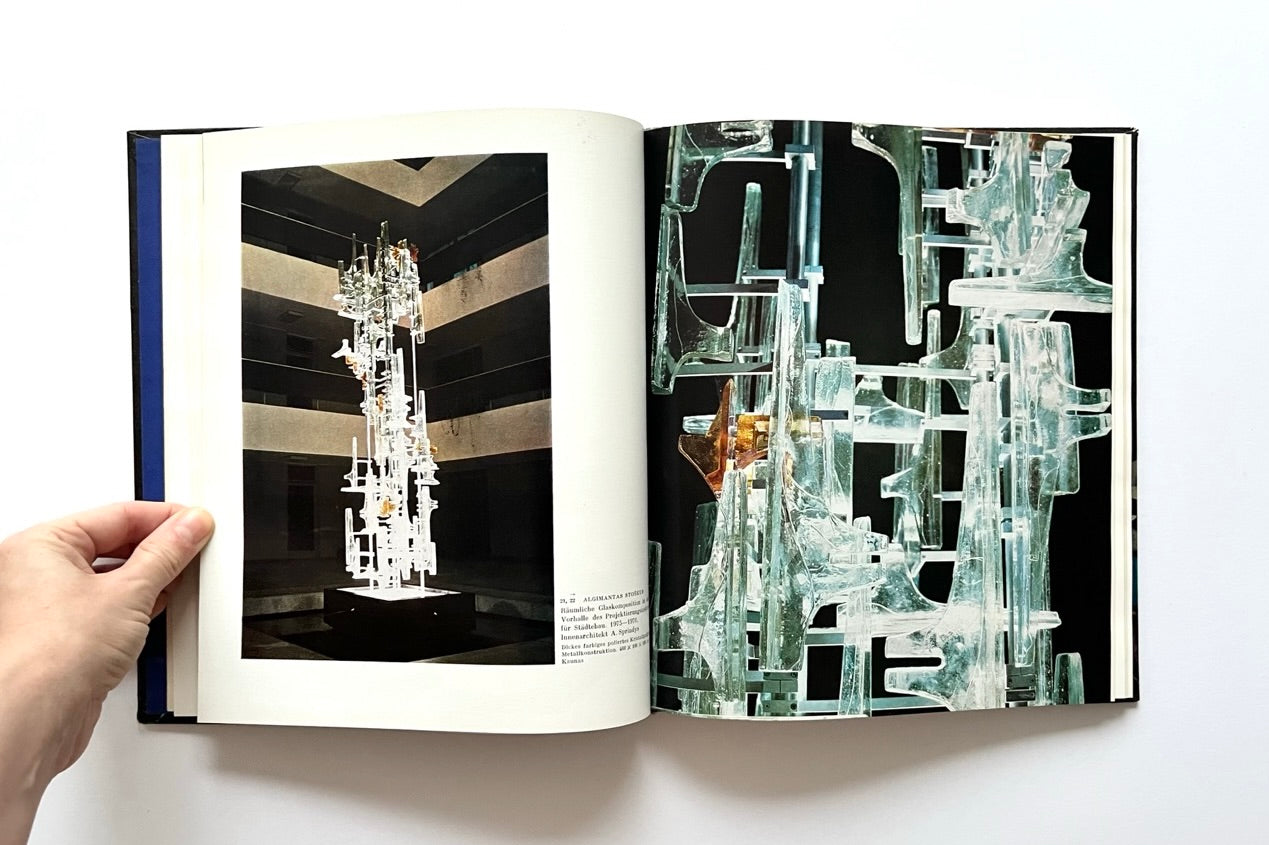 Open book showing images of architectural glass designs with a hand holding it.