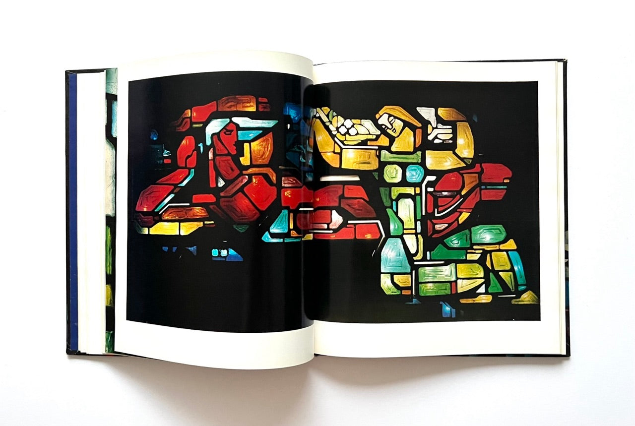 Open book -'Moderne litauische Glasmalerei' - displaying a colorful abstract stained glass art design on a black background