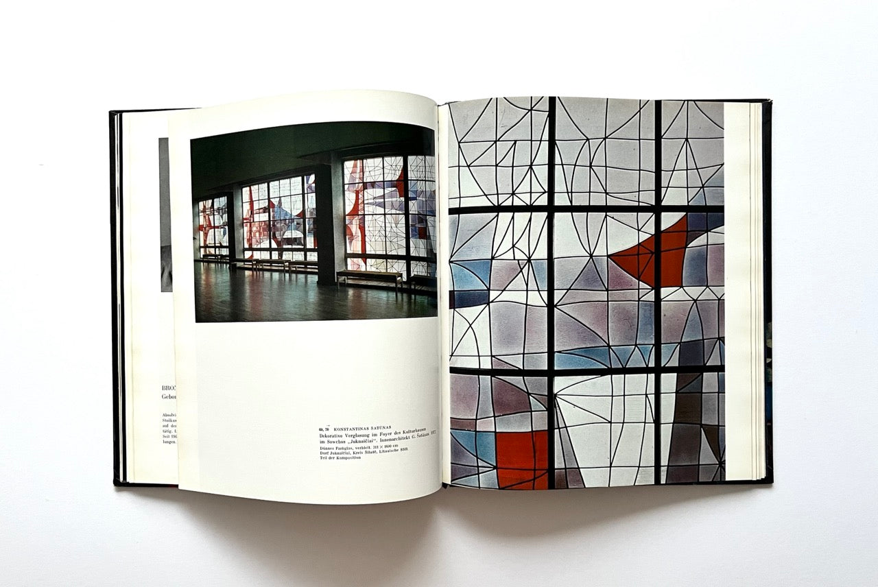 Open book - 'Moderne litauische Glasmalerei'  - showing a page with a modernist abstract stained glass window and another with an interior scene.