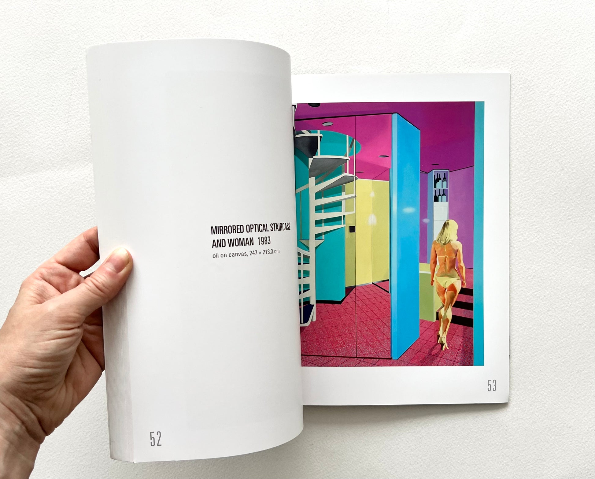An open 'Neil Stokoe: Paintings from the 60s on' book showing an artwork with a woman in bikini seen from the back, walking through a colorful interior featuring a spiral staircase. 