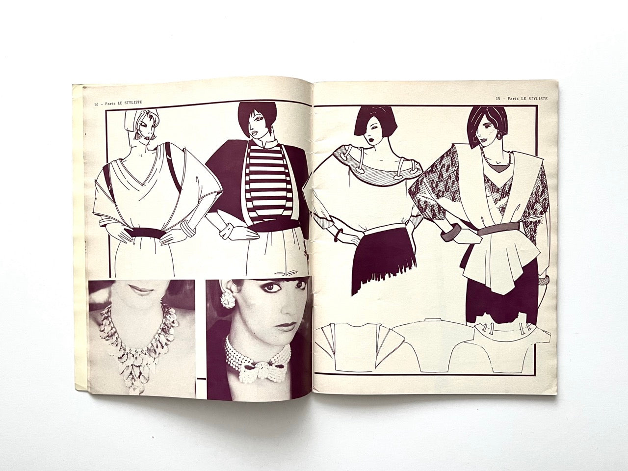 Interior spread from Paris Le Styliste No. 15. (1985) showing four illustrated women in voluminous 80s tops with draped necklines, wide shoulders and belted waists; lower section includes black-and-white photos of statement necklaces and small technical garment drawings.