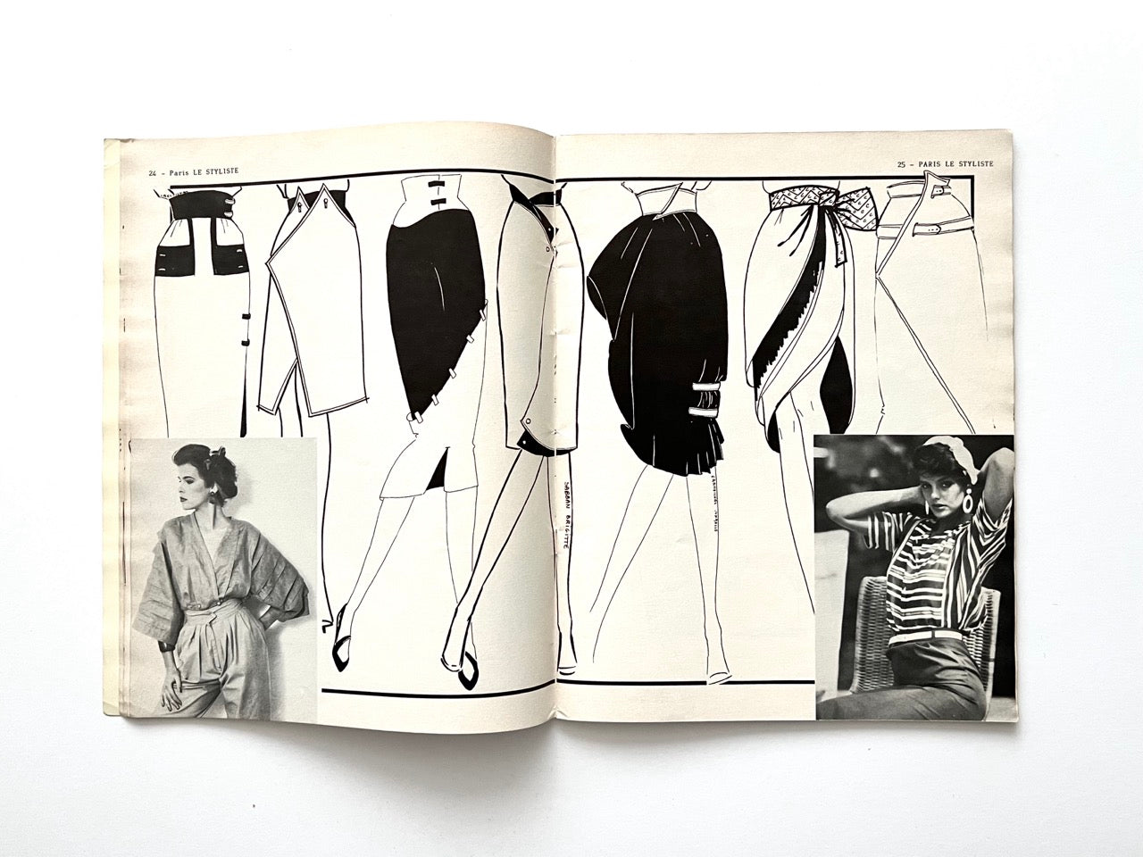 Spread from Paris Le Styliste No. 15 (1985) featuring wrap skirts and asymmetric dresses with bold black paneling and high necklines; inset black-and-white fashion photos show two women modelling 80s blouses and accessories.