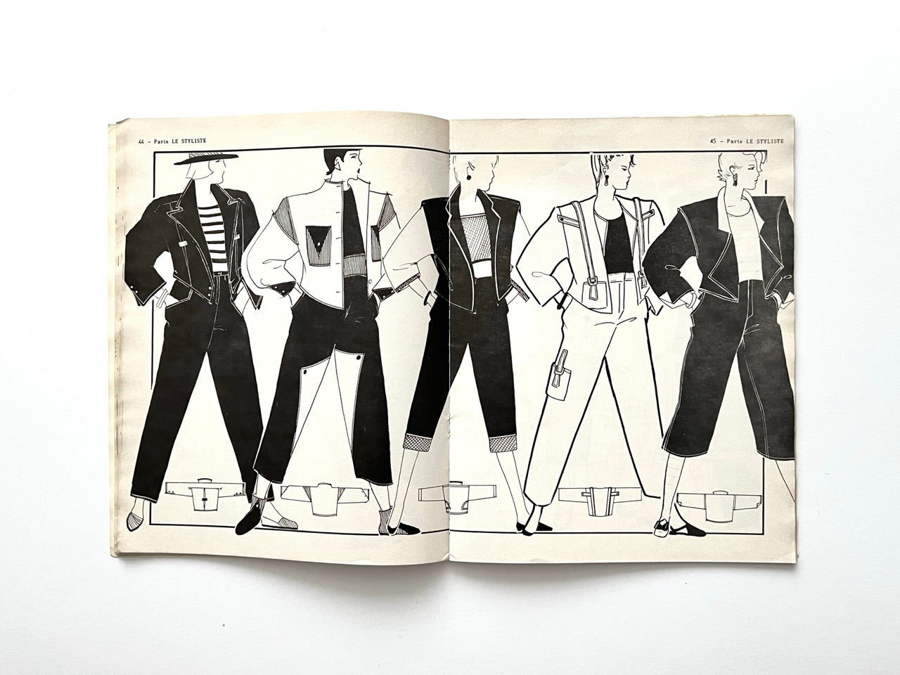 Two-page spread from Paris Le Styliste No. 15. (1985) showing five figures in casual 80s looks: oversized jackets, striped tops, cropped trousers and high-waisted jeans with strong shoulder silhouettes; small bag and pocket details appear throughout.